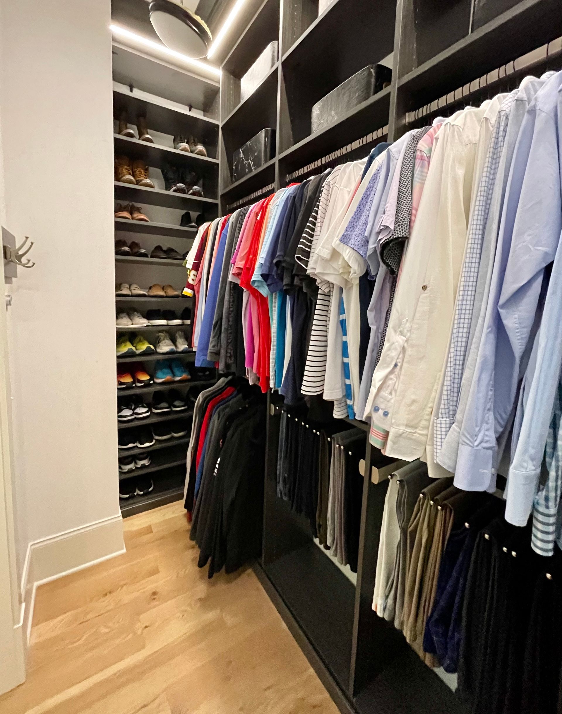 A walk in closet filled with lots of clothes and shoes.