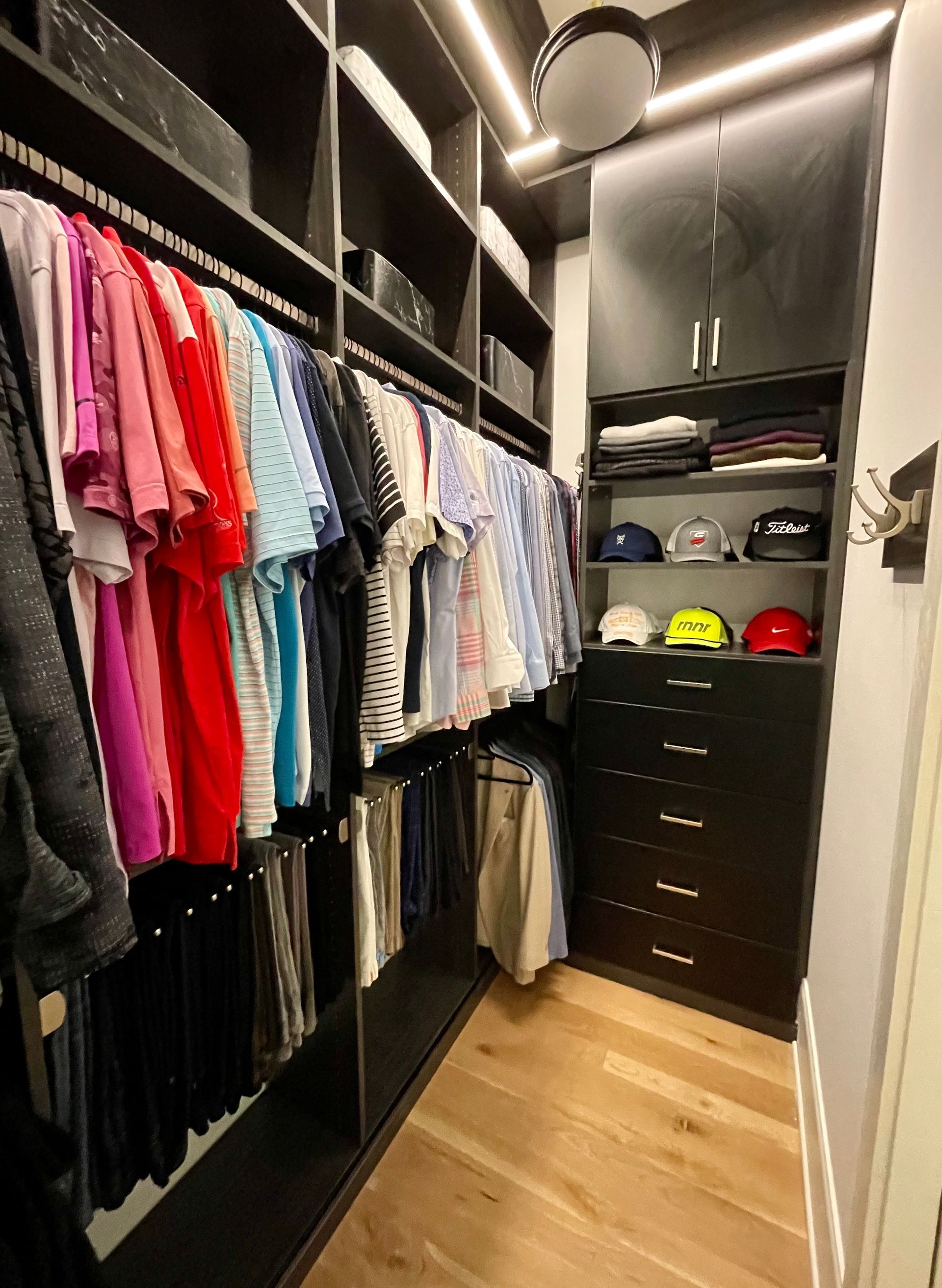 A walk in closet filled with lots of clothes and hats.