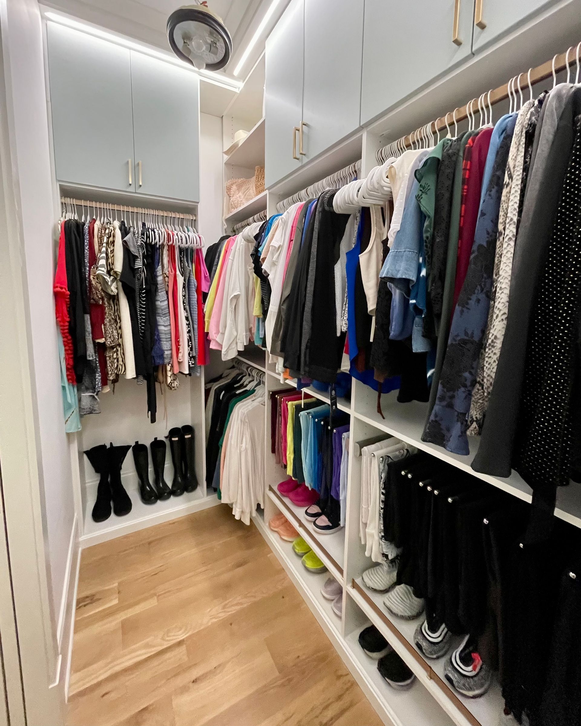 A walk in closet filled with lots of clothes and shoes.