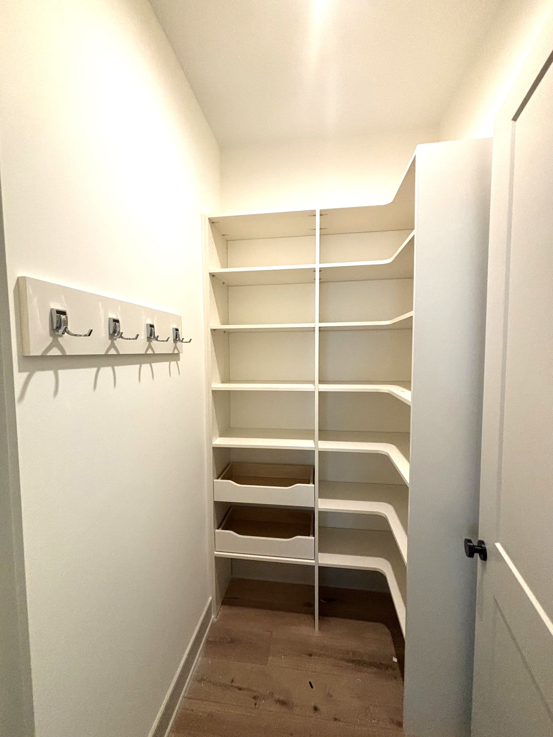 A walk in closet with shelves and drawers and a door.