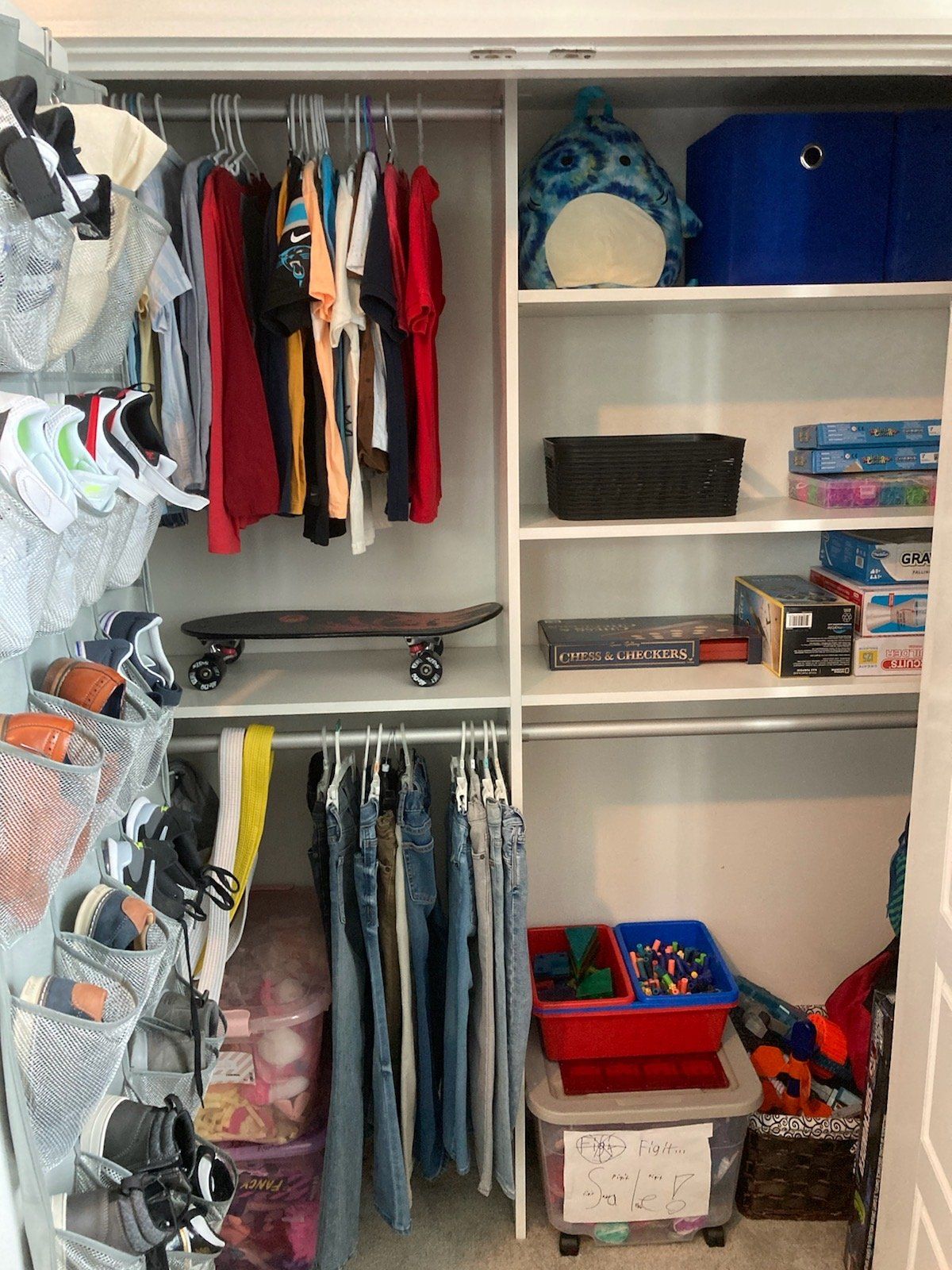 A closet filled with clothes , toys , and a skateboard.