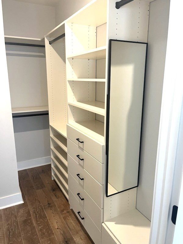 A walk in closet with lots of shelves and drawers and a mirror.