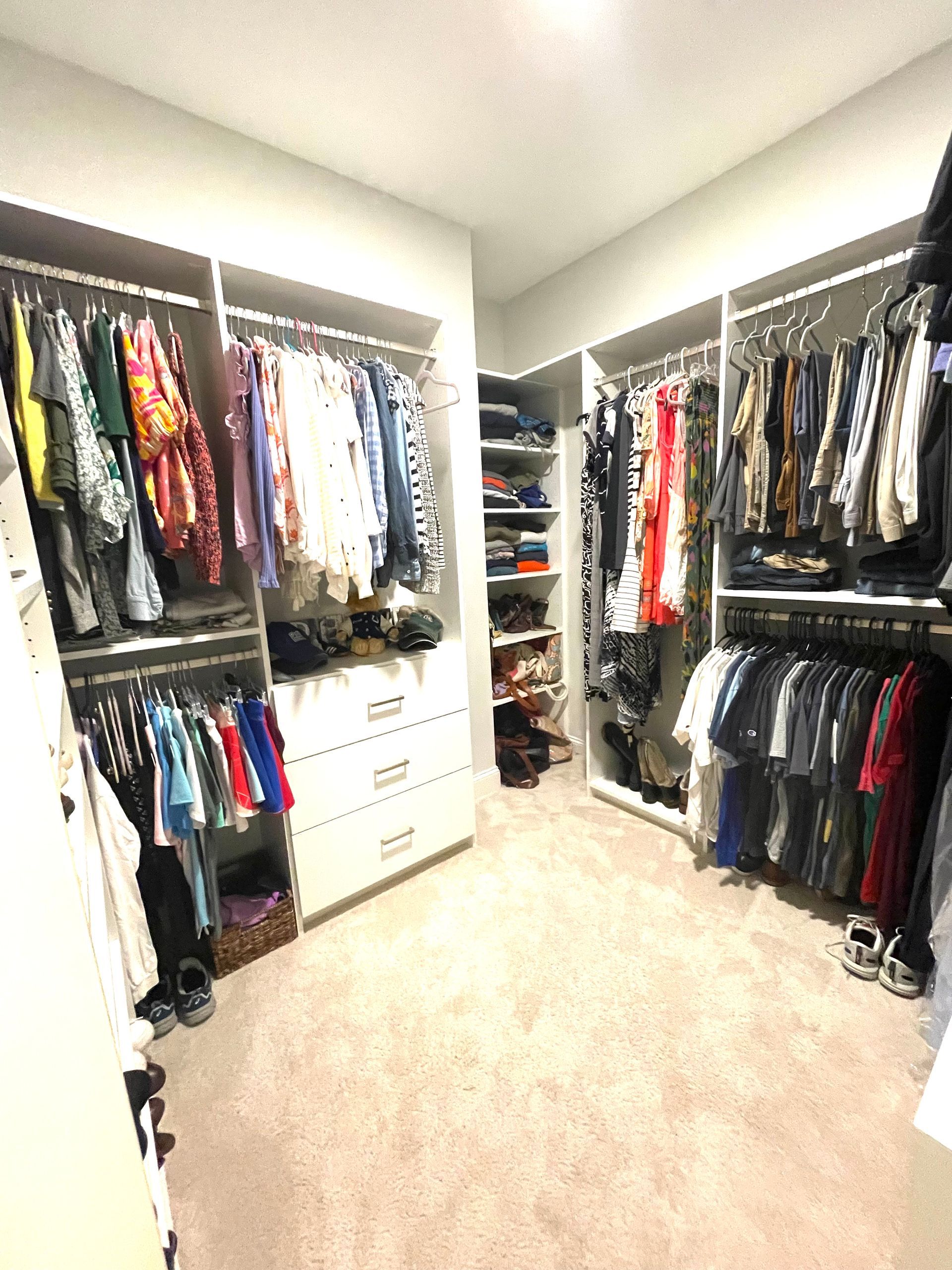 A walk in closet filled with lots of clothes and shoes.