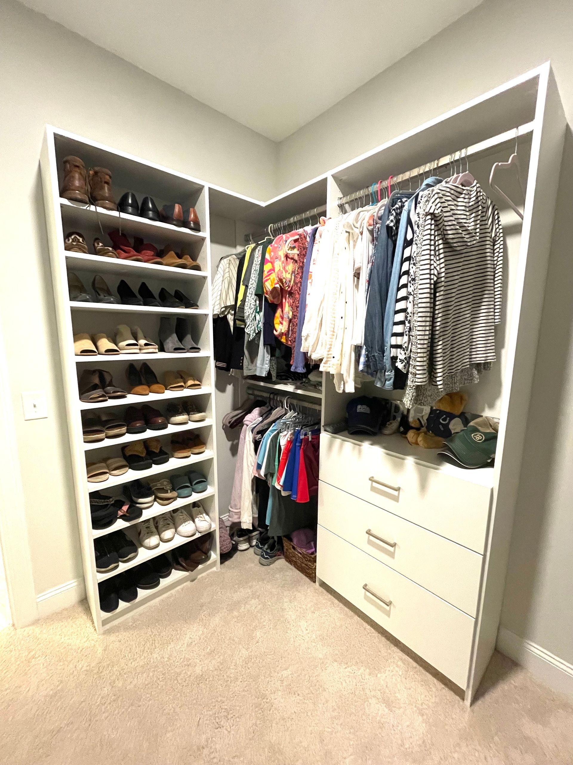 A walk in closet filled with lots of clothes and shoes.