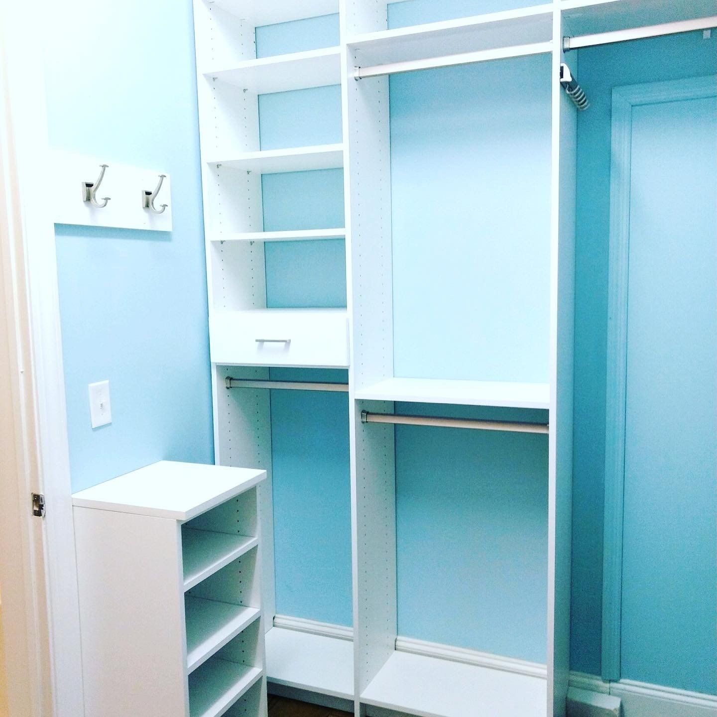 A walk in closet with blue walls and white shelves