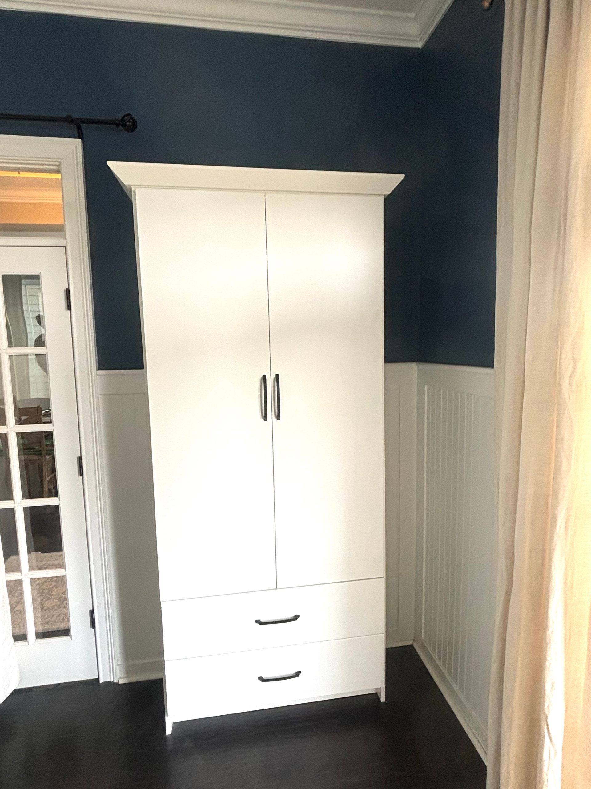 A white cabinet with drawers in a room with blue walls