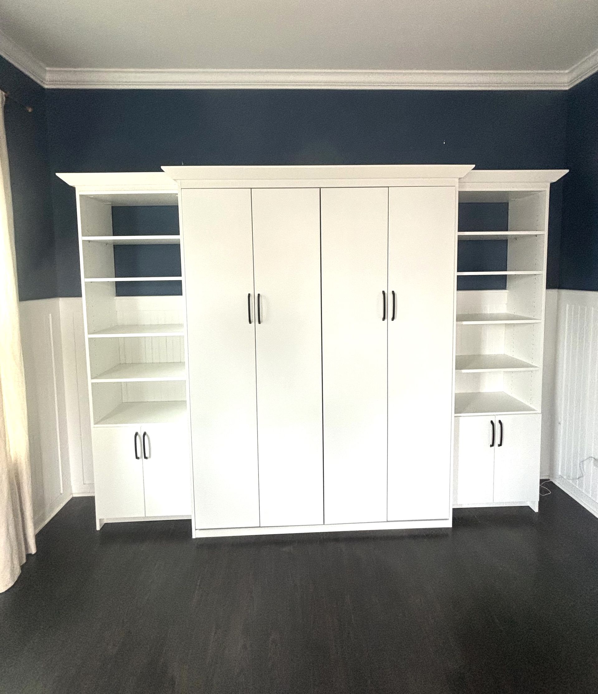 A room with blue walls and white cabinets and shelves