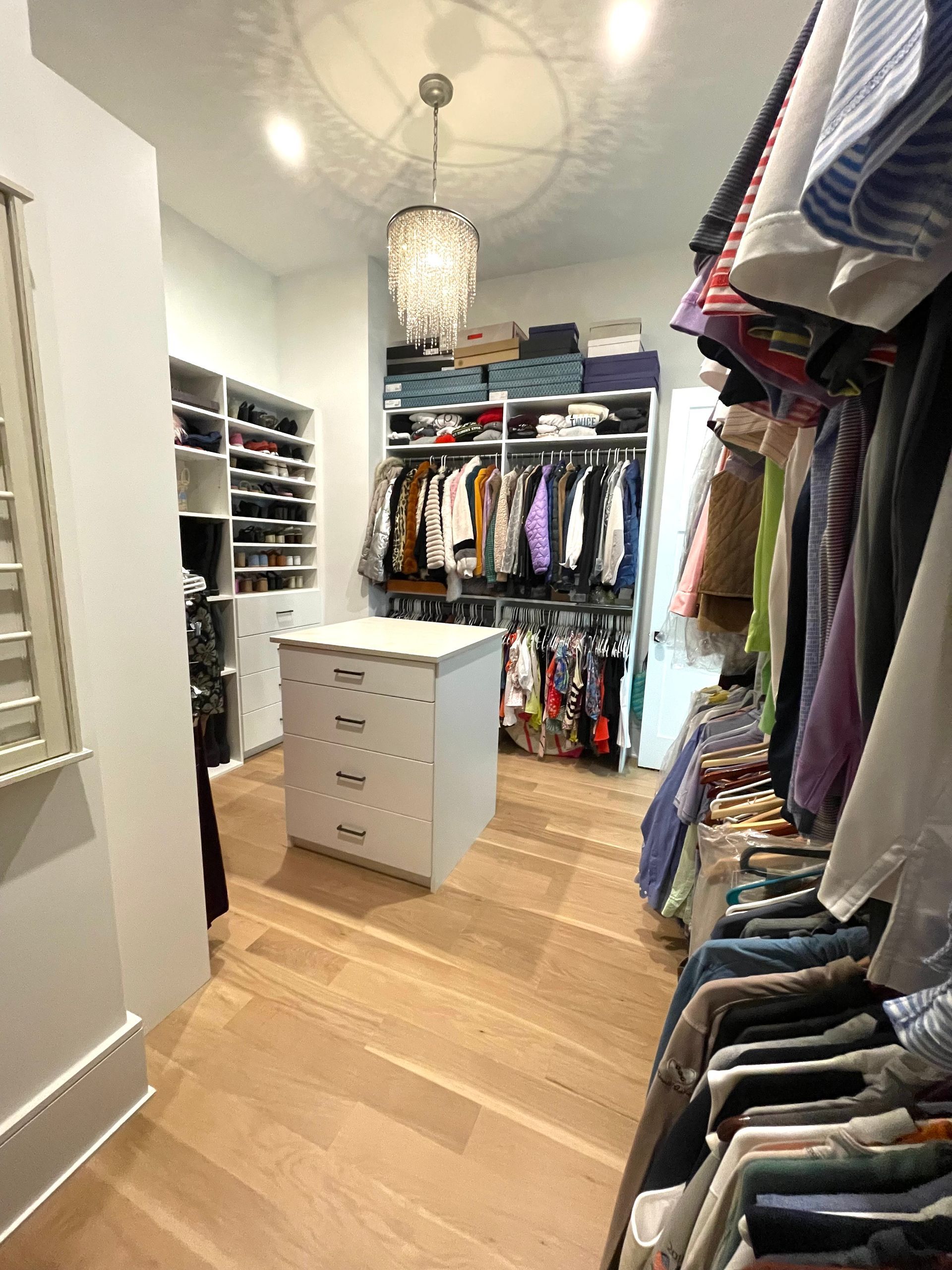 A walk in closet filled with lots of clothes and a dresser.