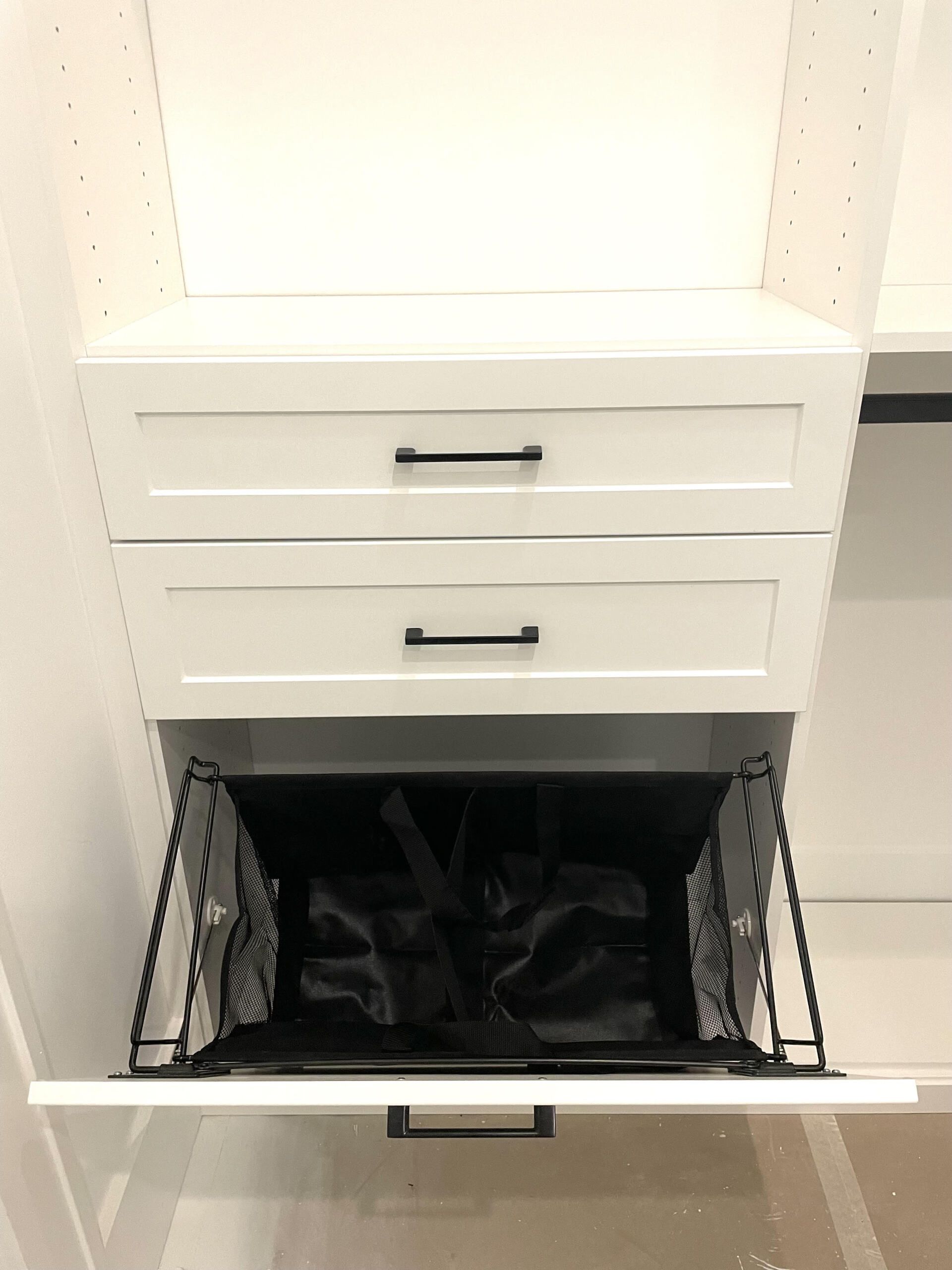 A closet with two drawers and a laundry basket in it.