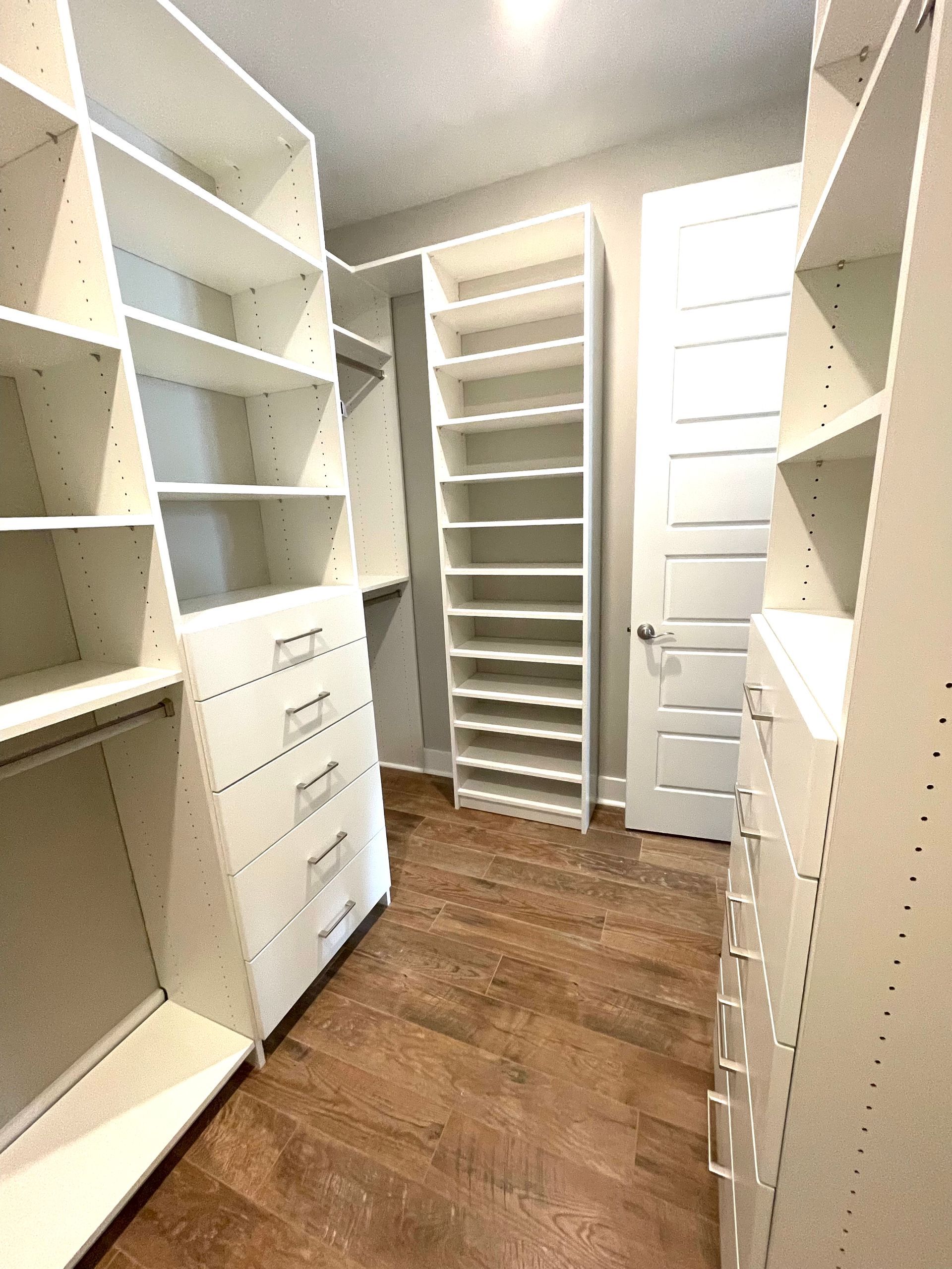 A walk in closet with lots of shelves and drawers.