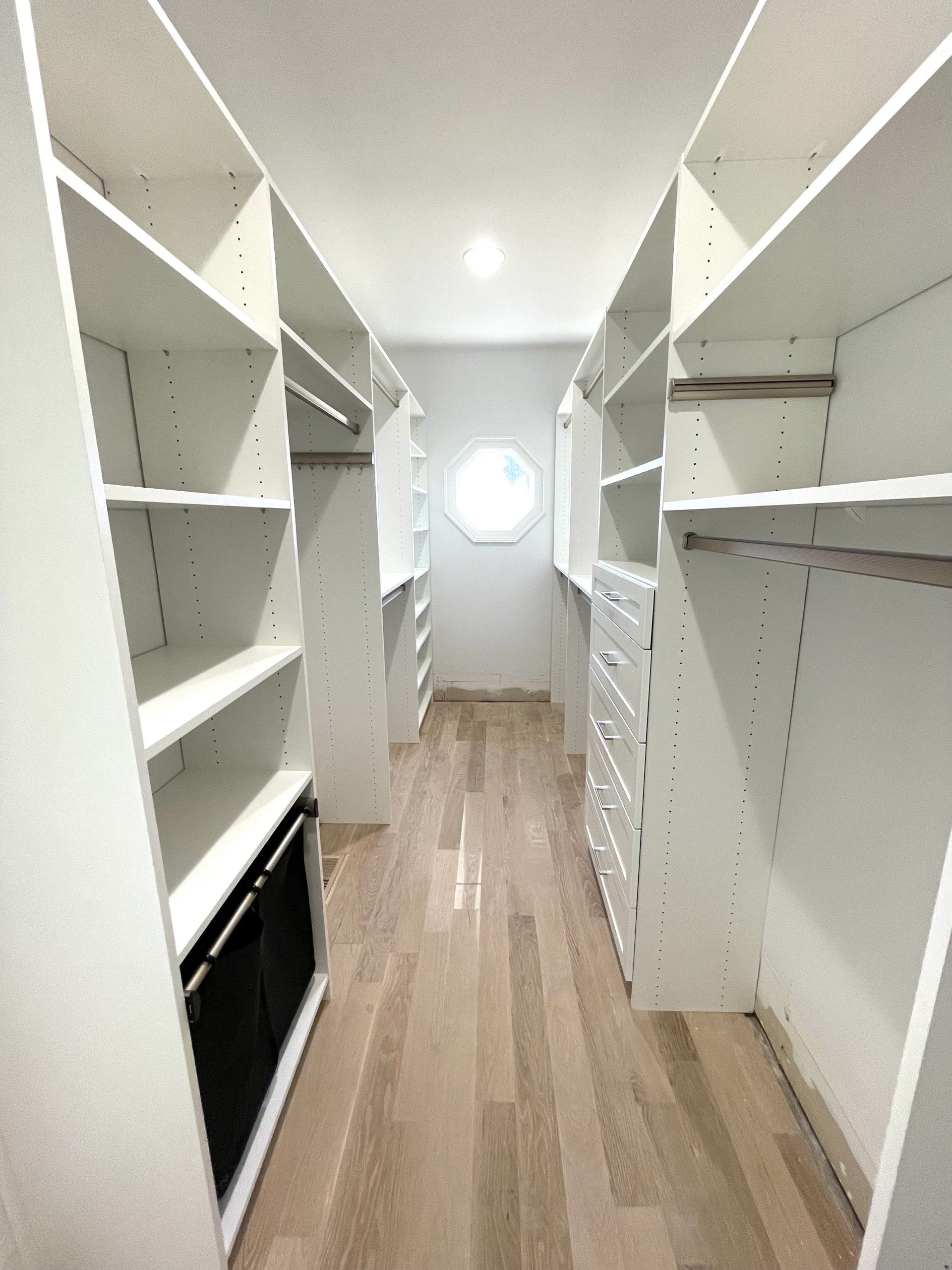 A walk in closet with lots of shelves and drawers