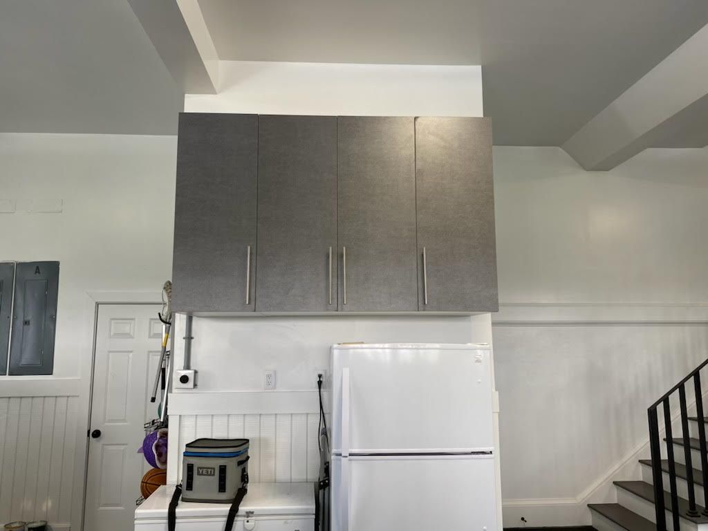 A kitchen with gray cabinets and a white refrigerator
