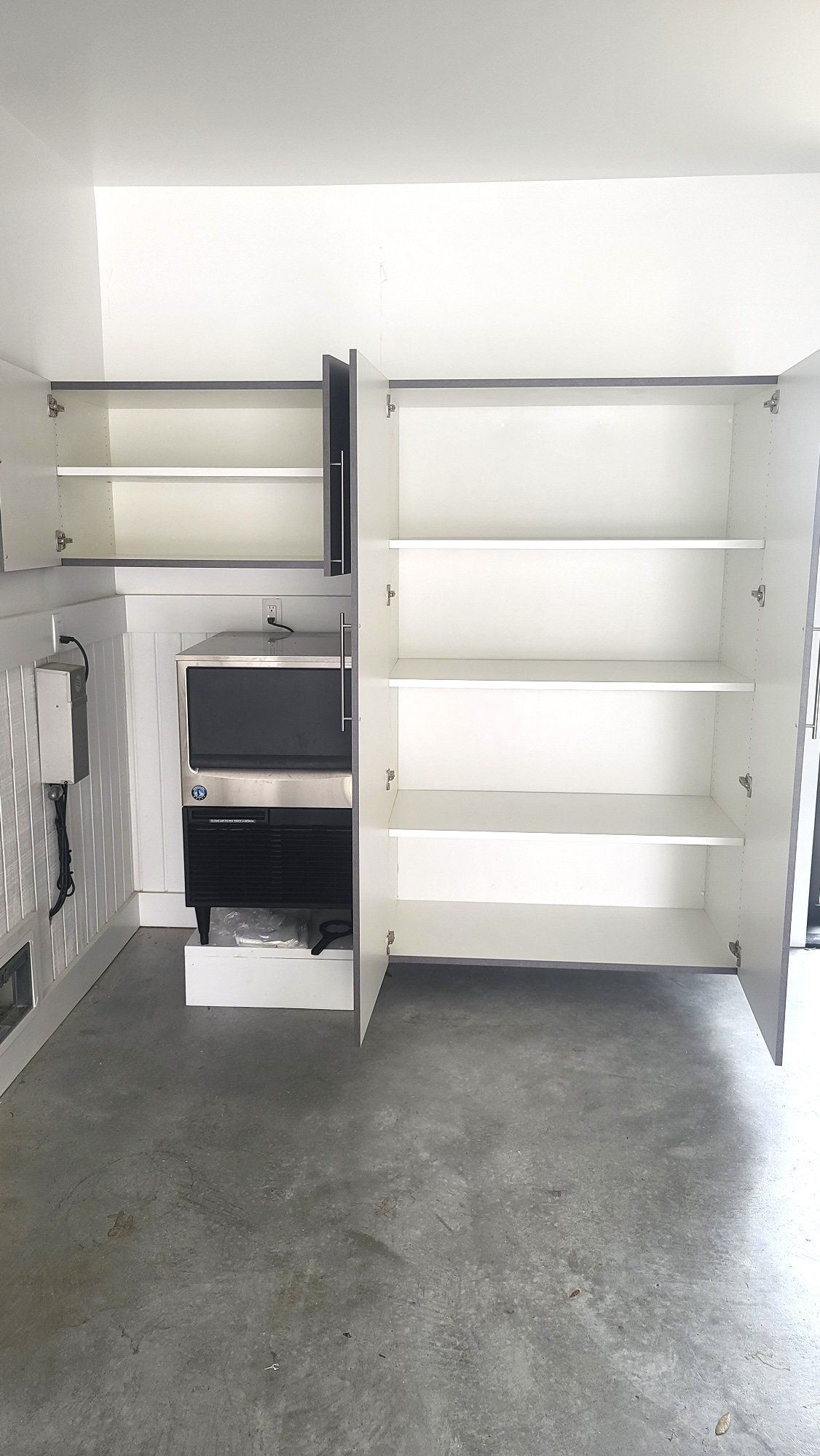 A kitchen with a microwave and shelves in it.