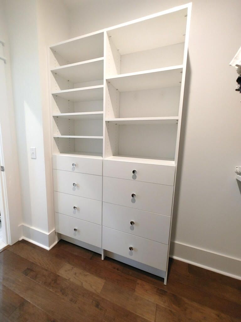 A walk in closet with lots of shelves and drawers.