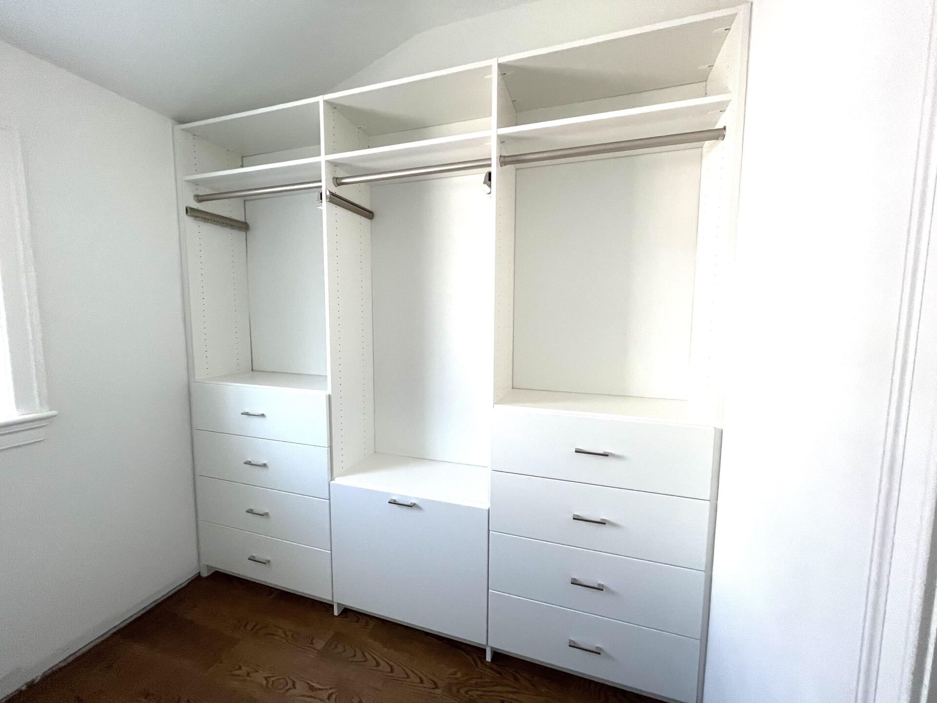 A walk in closet with white shelves and drawers in a bedroom.