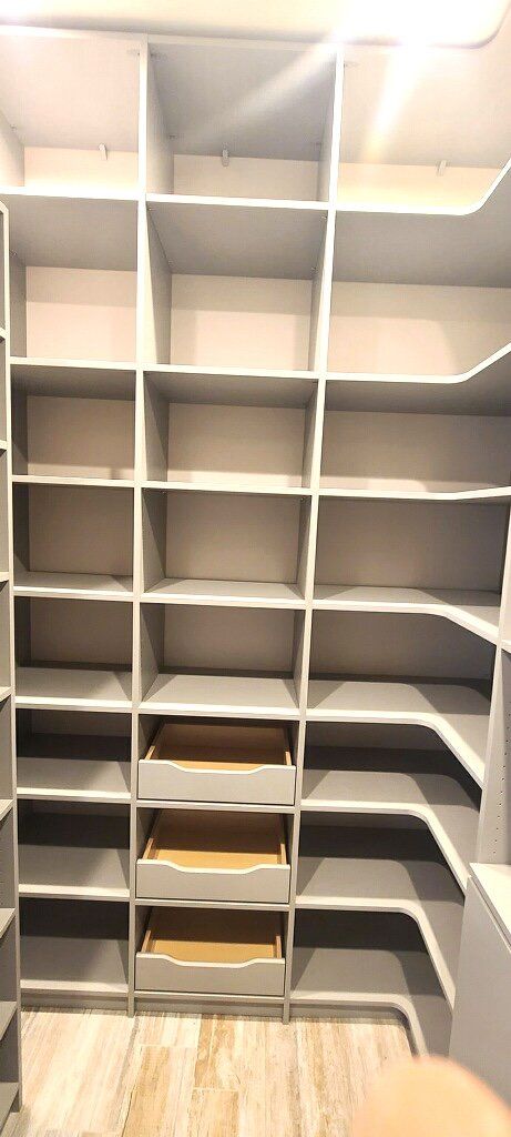 A walk in closet with lots of shelves and drawers.