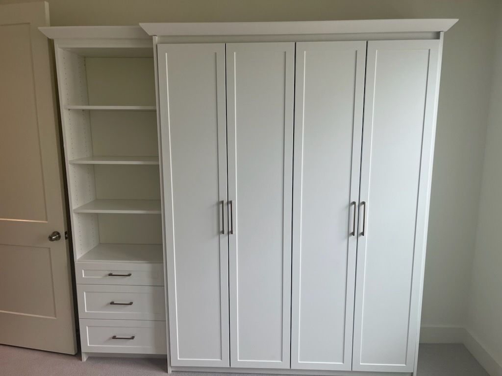 A white wardrobe with shelves and drawers in a room