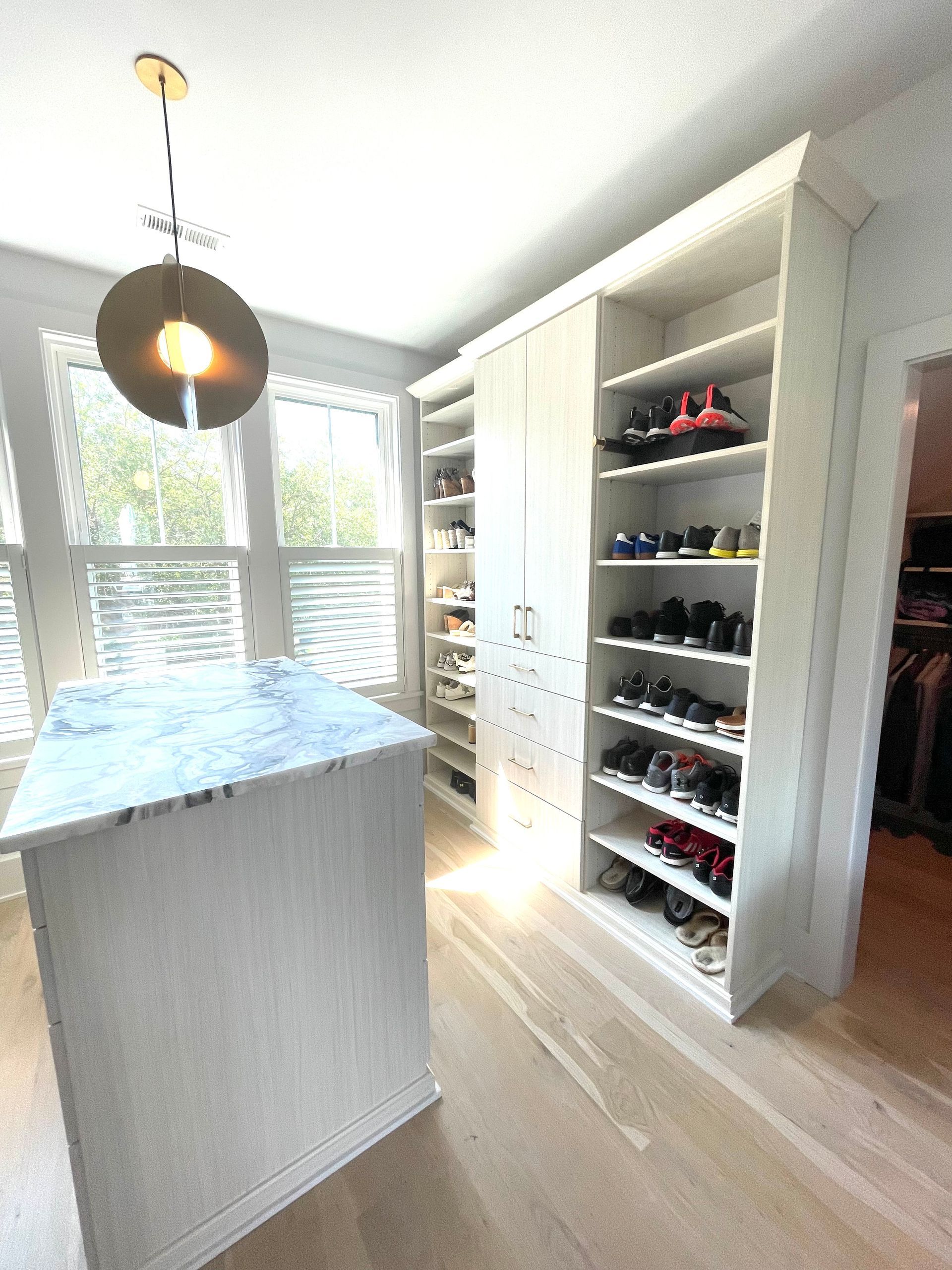 A walk in closet with lots of shelves and a large island in the middle.