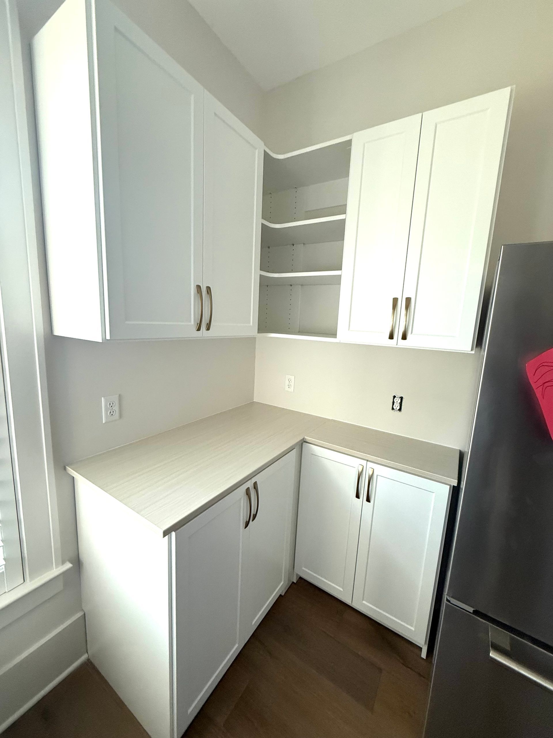 A kitchen with white cabinets and a black refrigerator