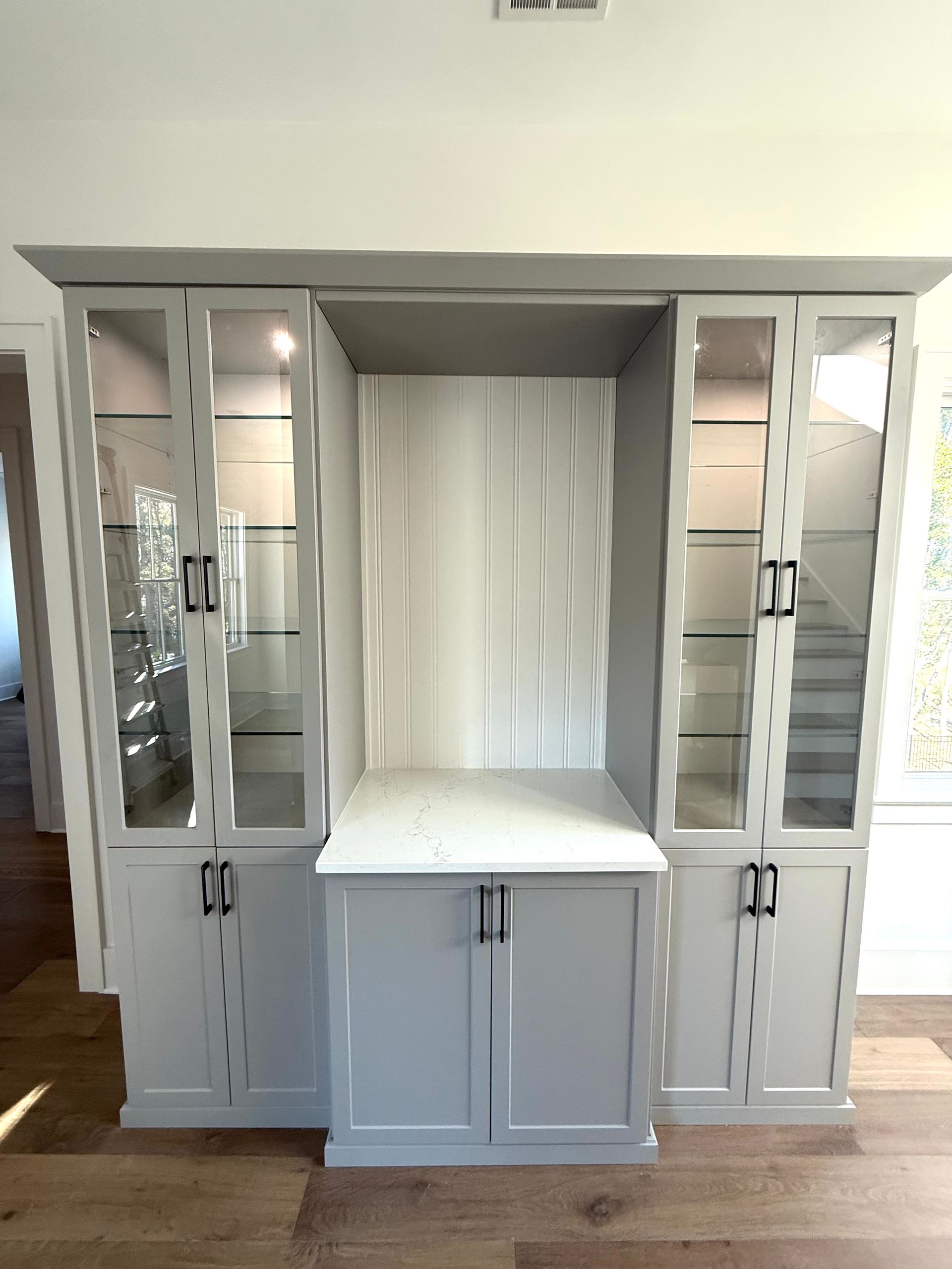 A large cabinet with glass doors and shelves in a living room.