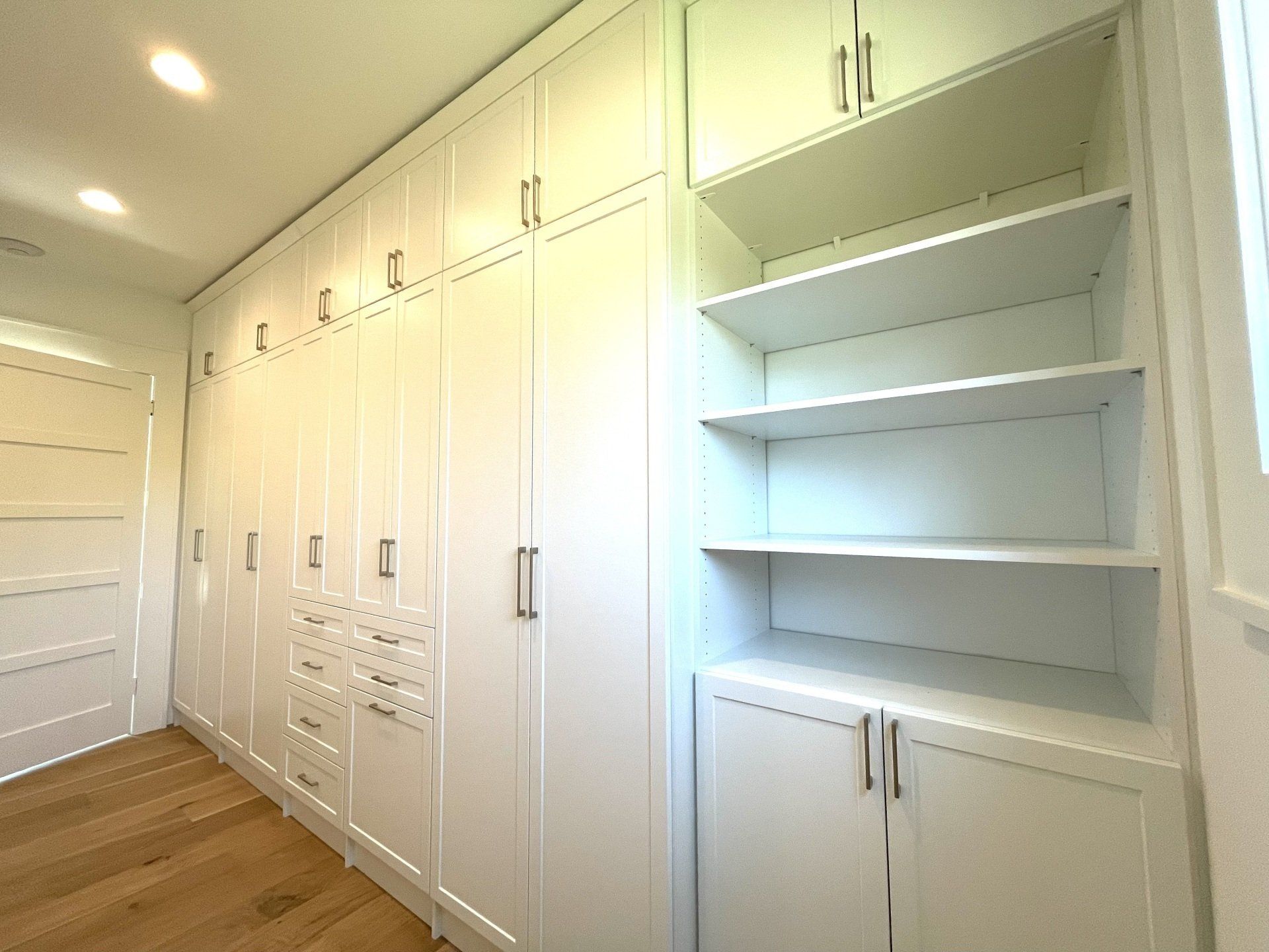 A room with a lot of white cabinets and shelves