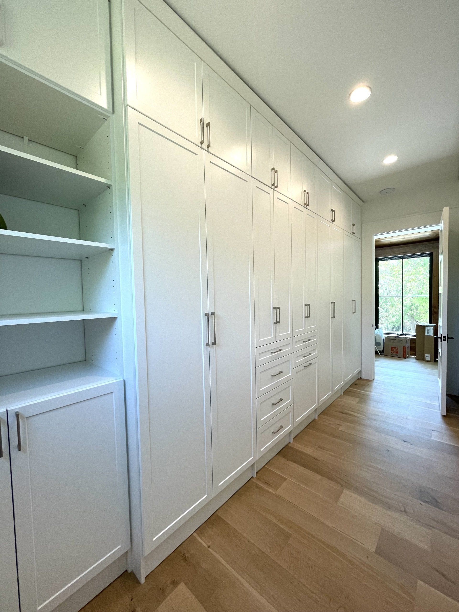 A room with a lot of white cabinets and shelves