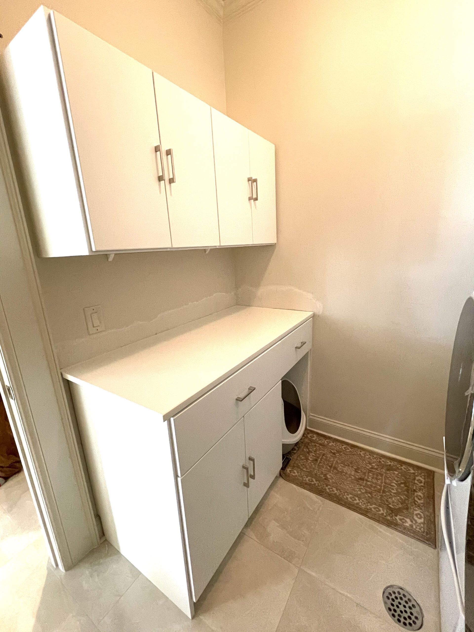 A laundry room with white cabinets and a washer and dryer