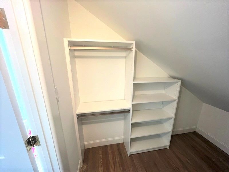 A small closet with a slanted ceiling and shelves.