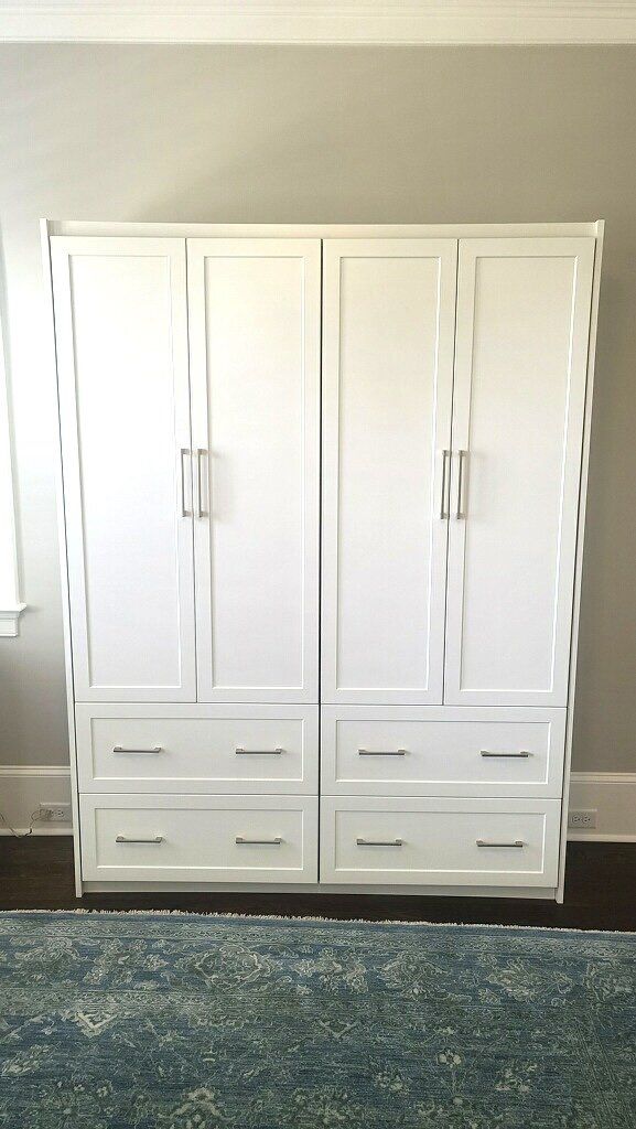 A large white cabinet with drawers and doors in a bedroom.
