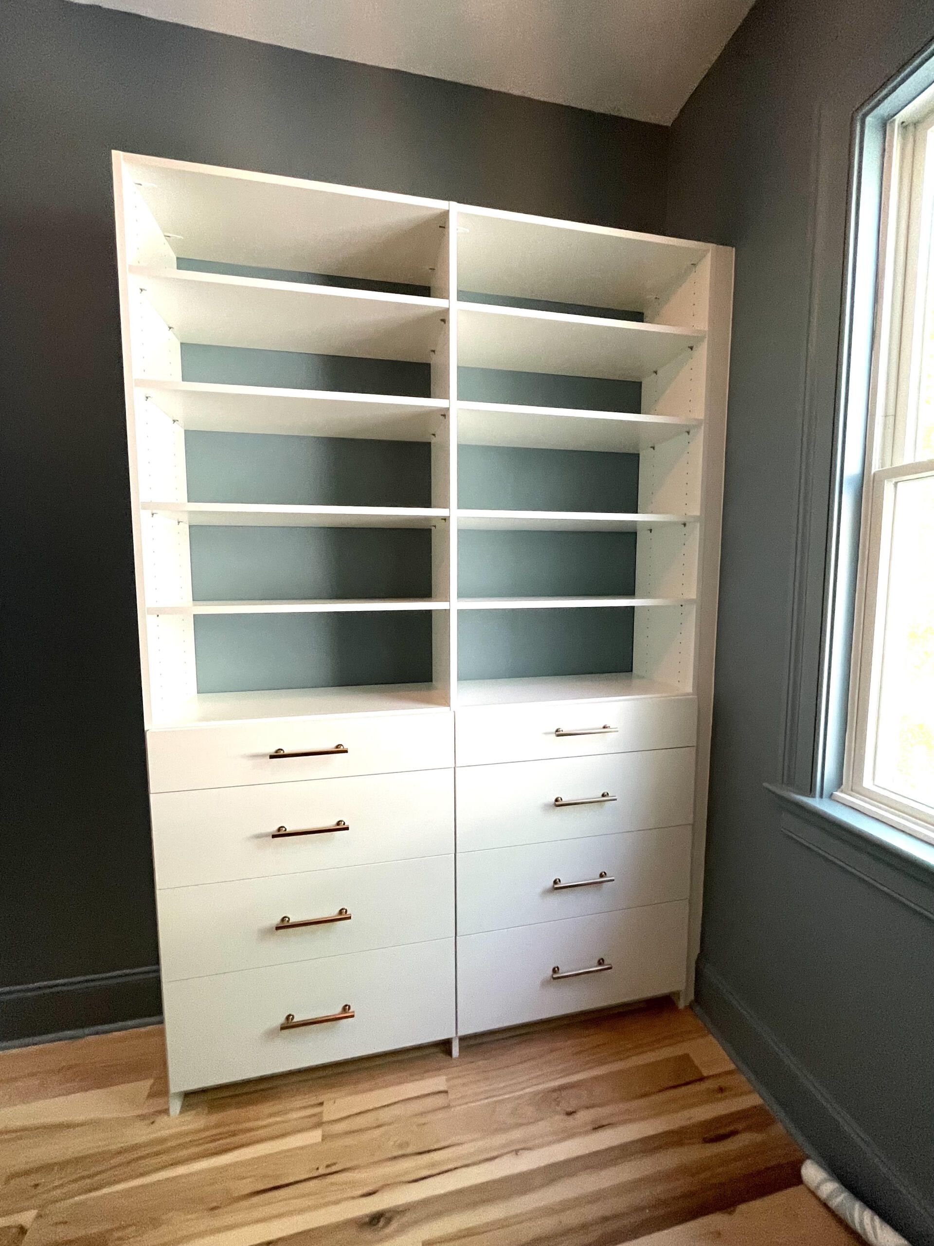 A closet with lots of shelves and drawers in a room with a window.
