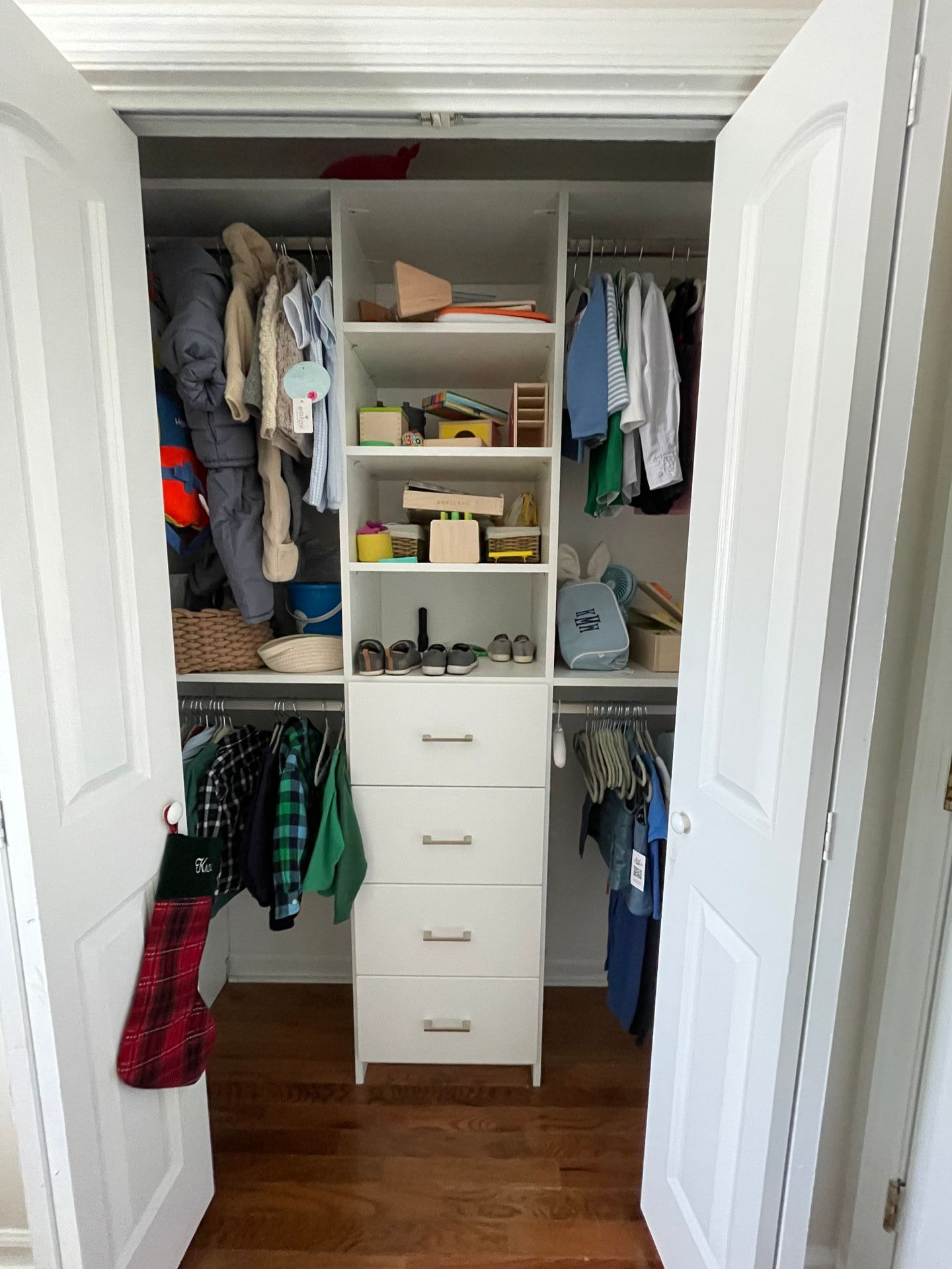 A closet filled with clothes and toys with the doors open.