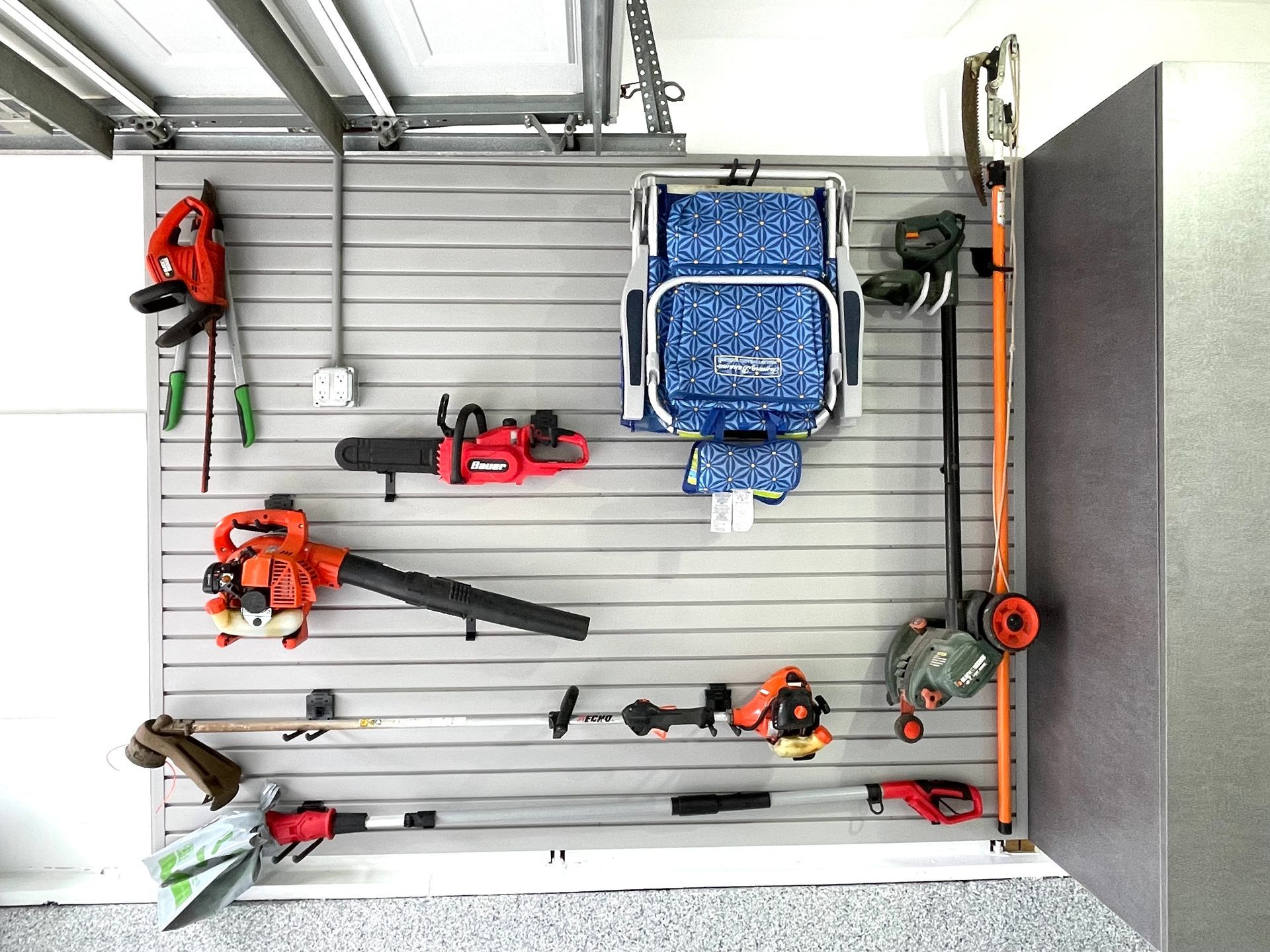 A bunch of tools are hanging on a wall in a garage.