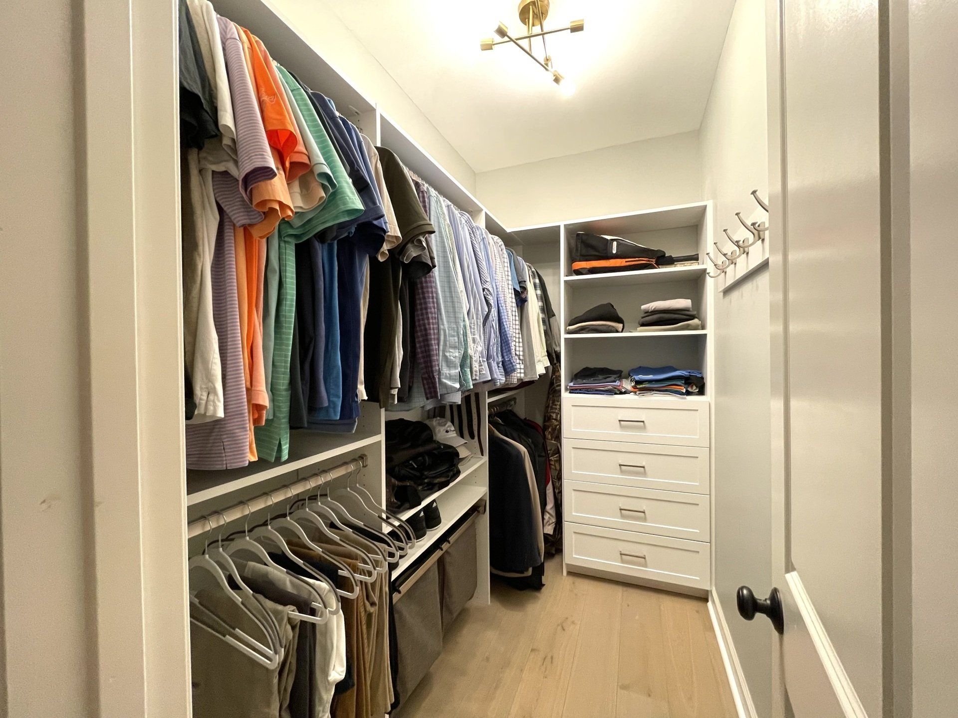 A walk in closet filled with clothes and dressers.