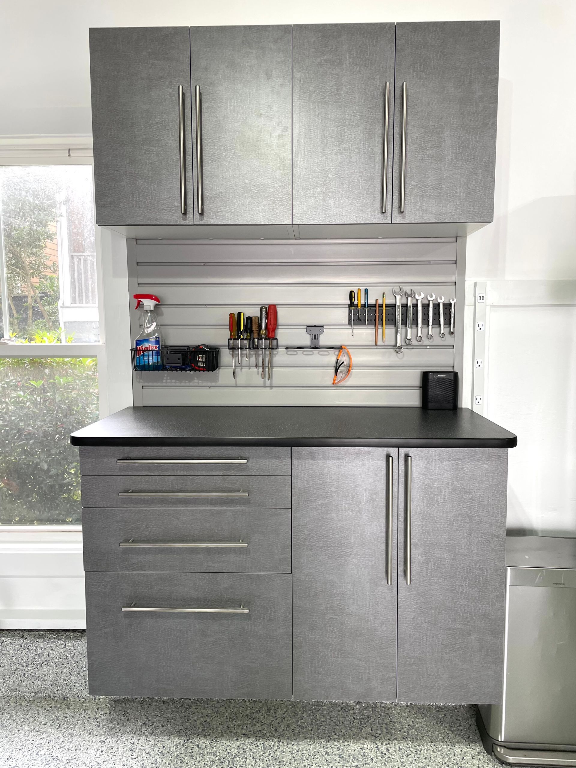 A kitchen with gray cabinets and a black counter top.