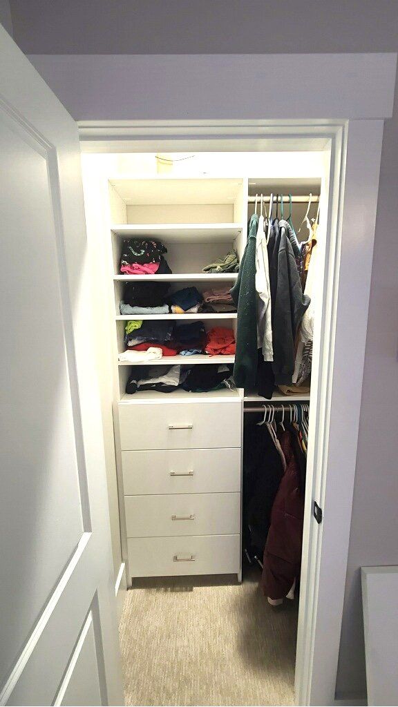 A closet with a lot of clothes in it and a door open.