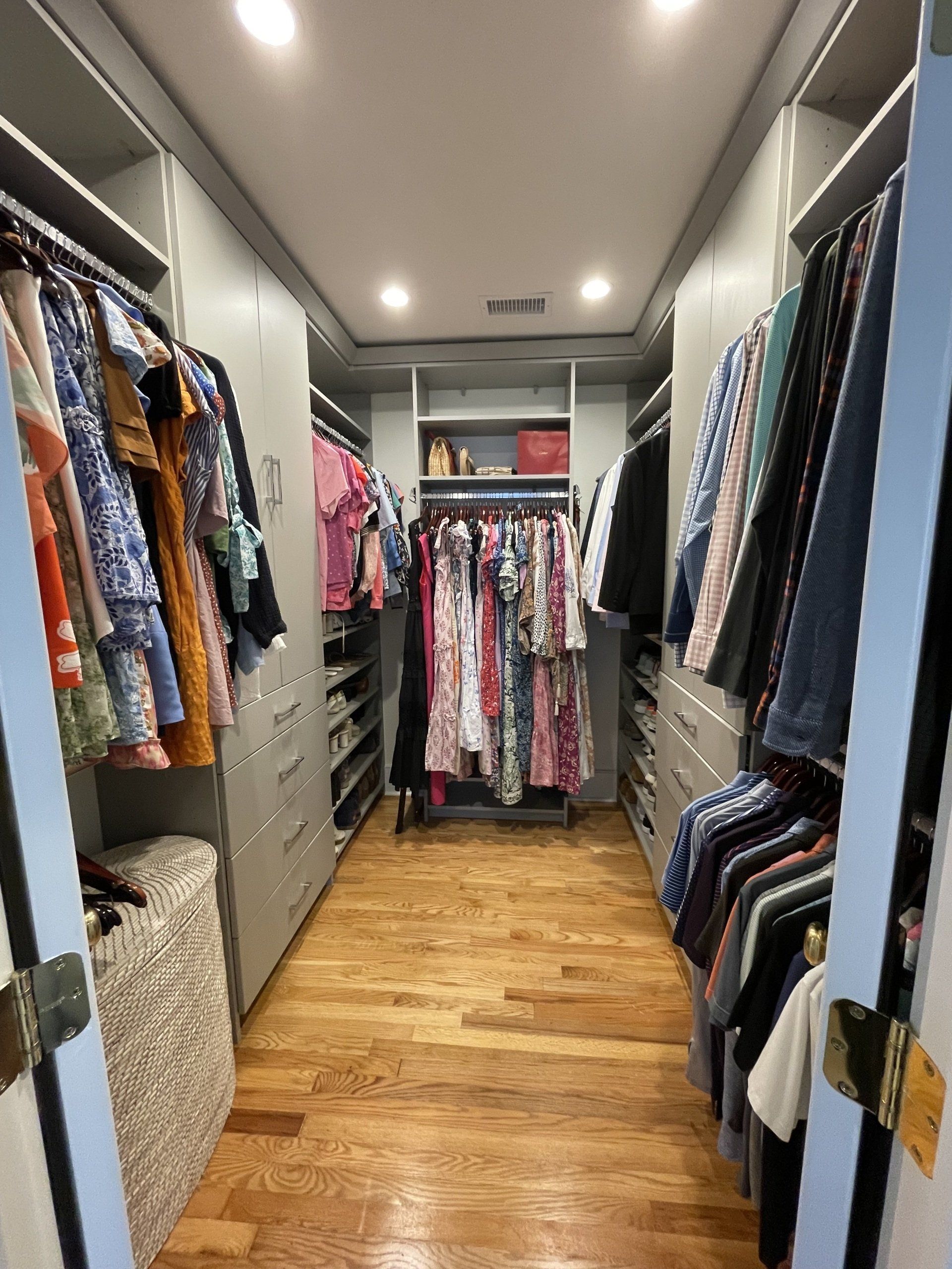 A walk in closet filled with lots of clothes and a wooden floor.