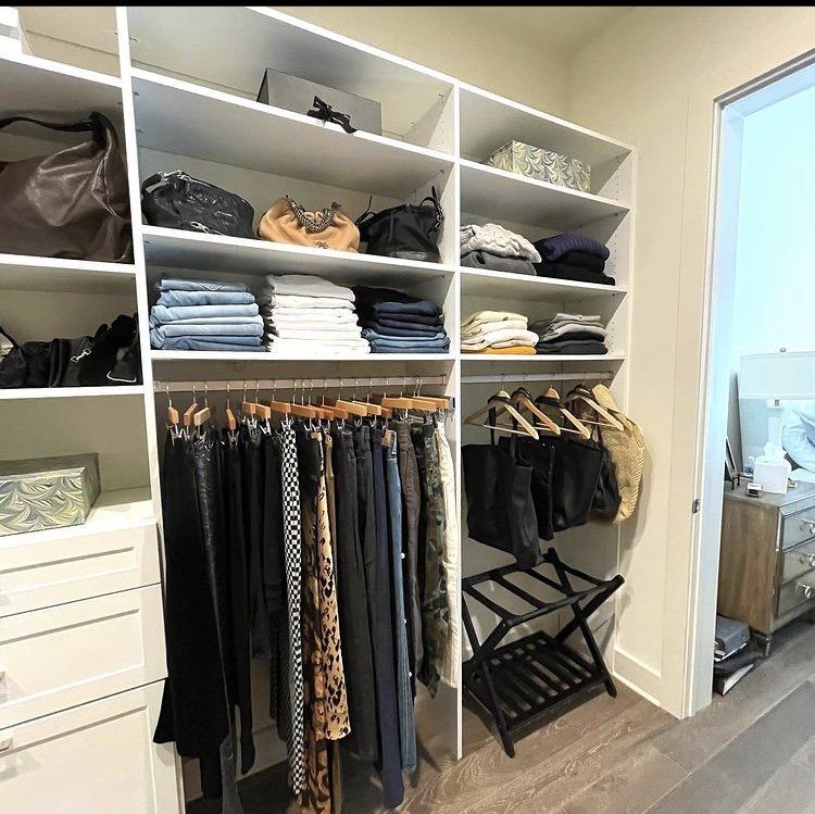 A walk in closet filled with clothes and bags