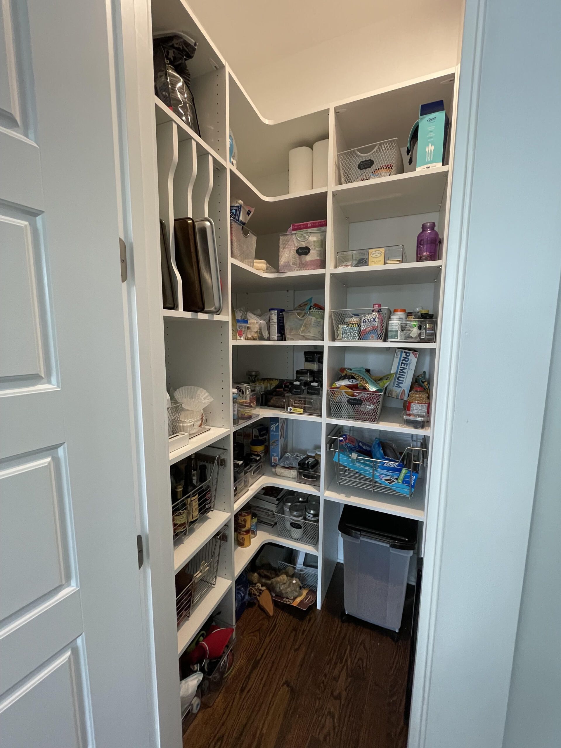 A pantry with lots of shelves and a trash can.