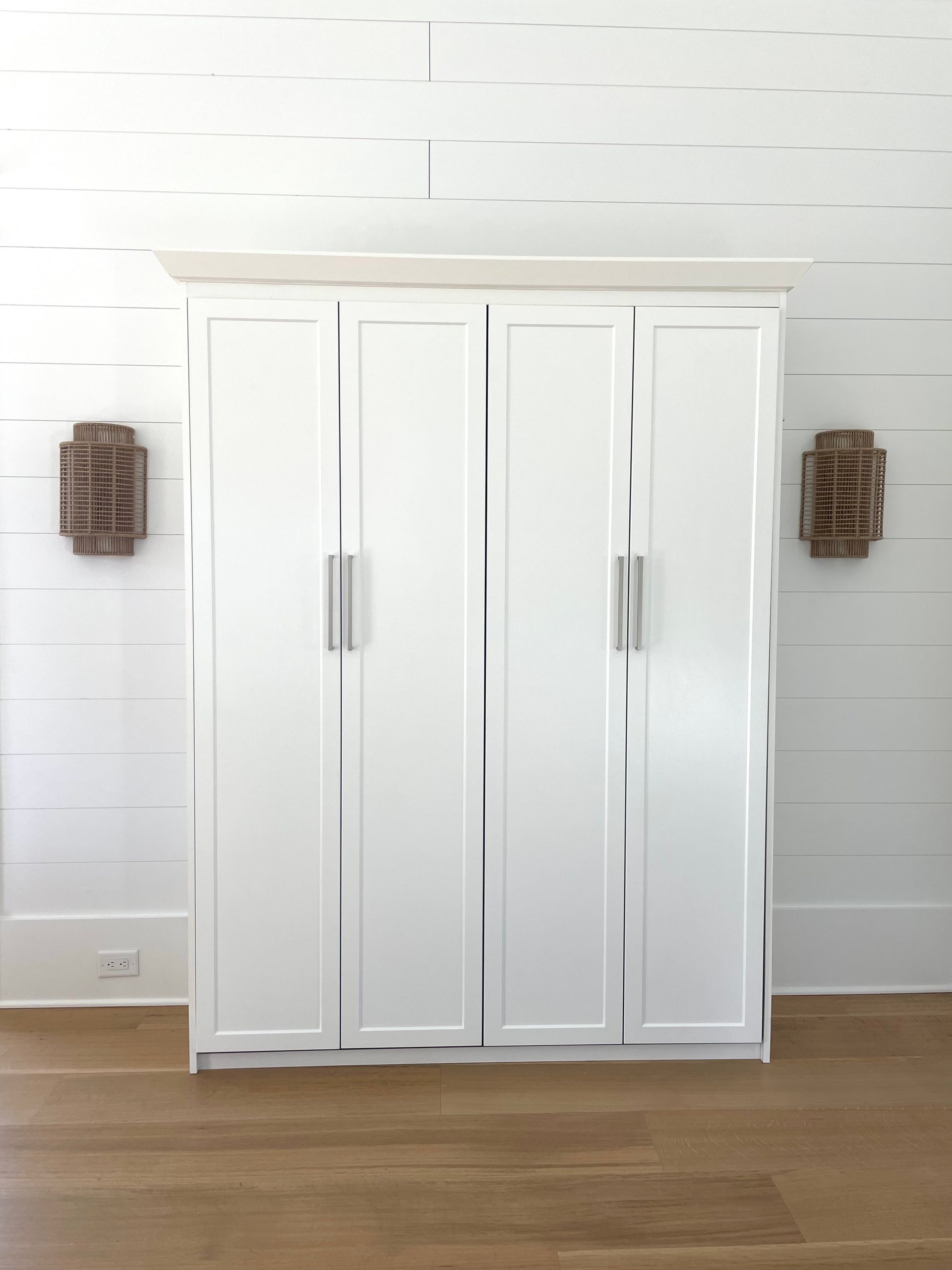 A large white cabinet is sitting on a wooden floor in a room.