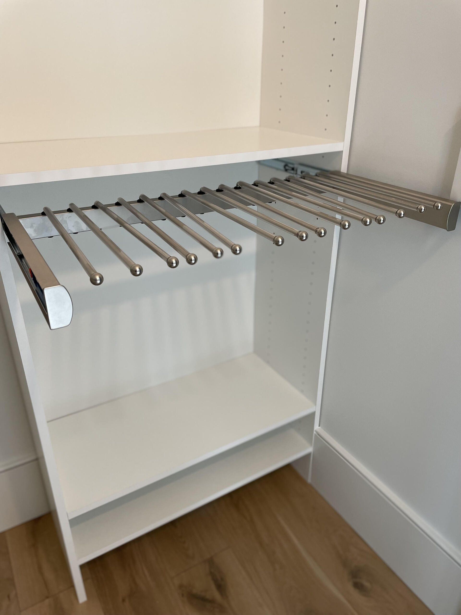 A closet with a pull out pants rack and a shelf.