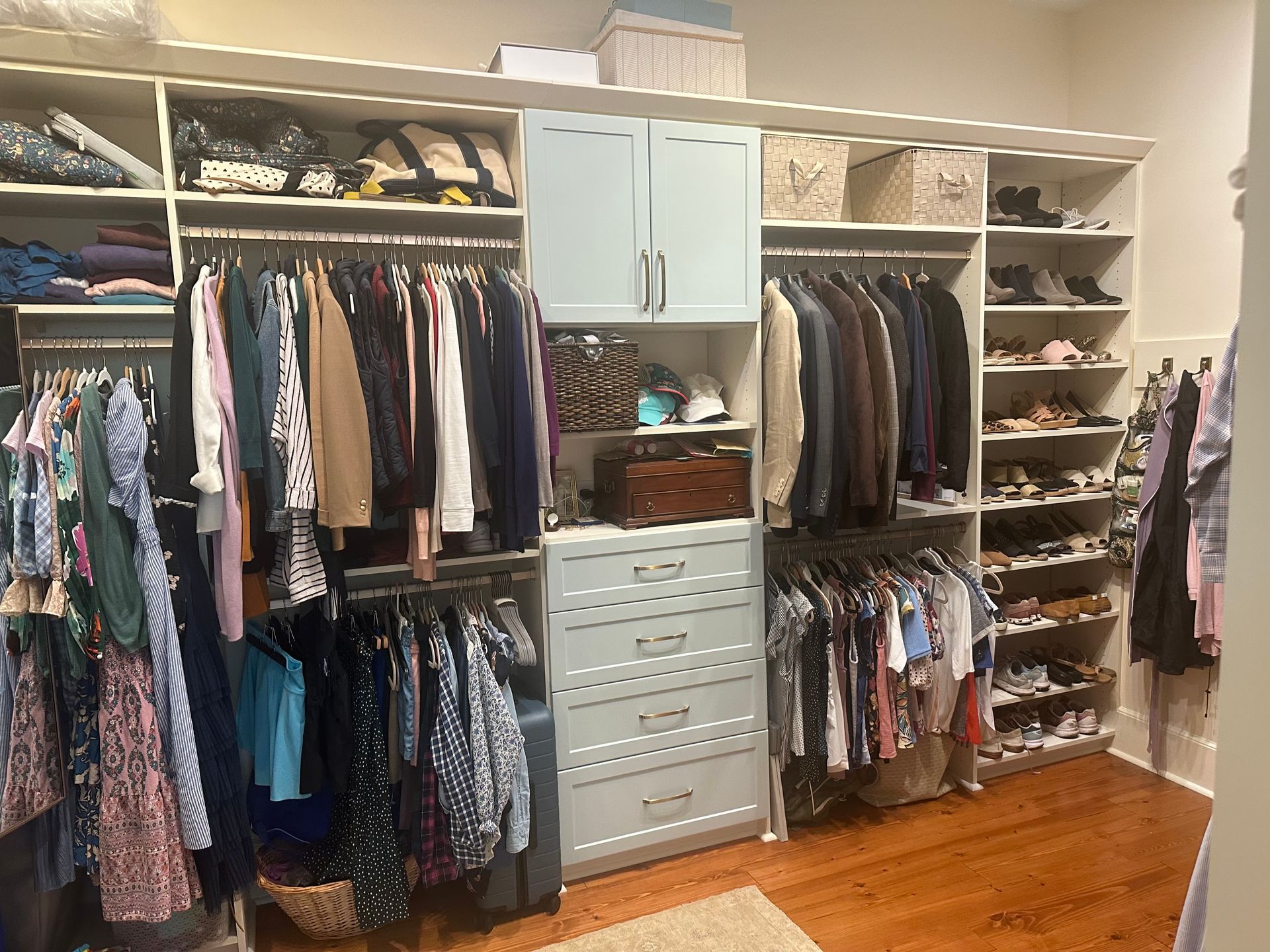 A walk in closet filled with lots of clothes and shoes.
