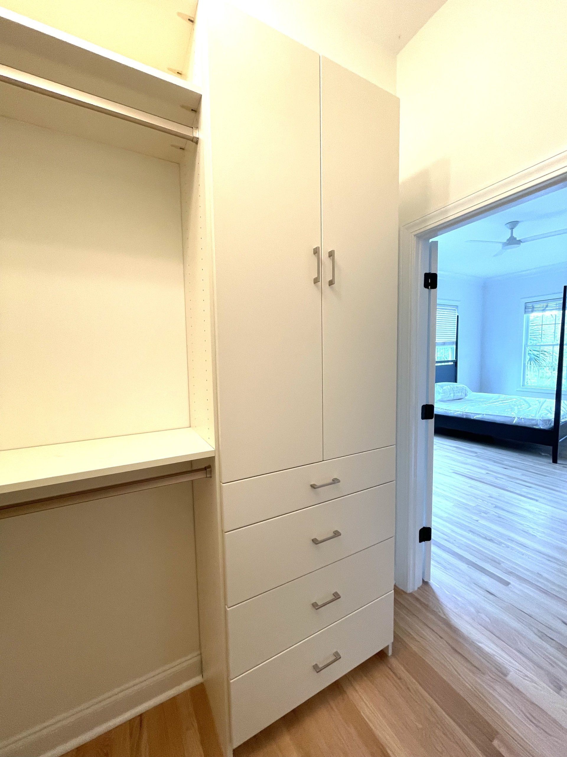 A walk in closet with a large white cabinet and drawers.