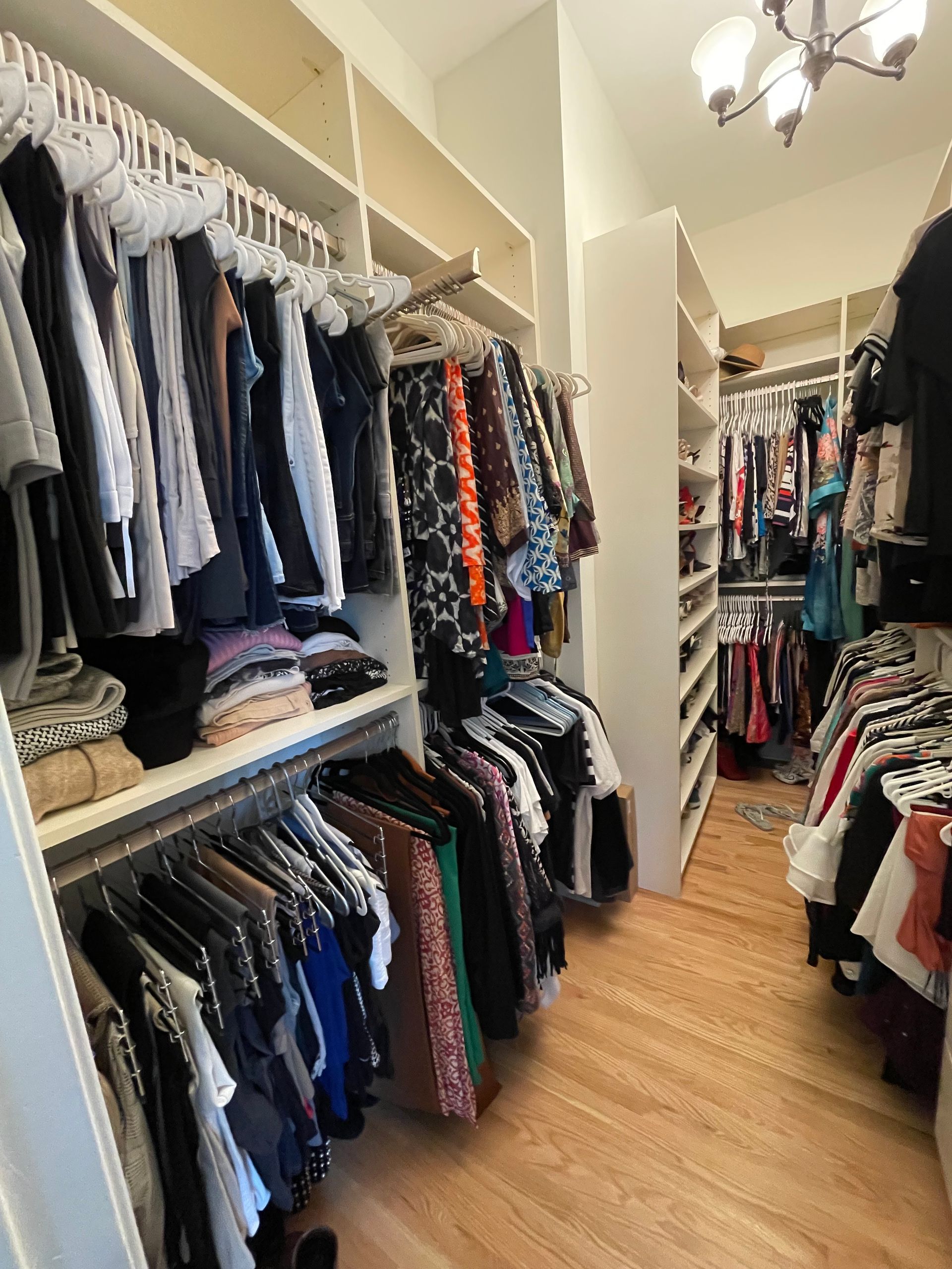 A walk in closet filled with lots of clothes and shoes.