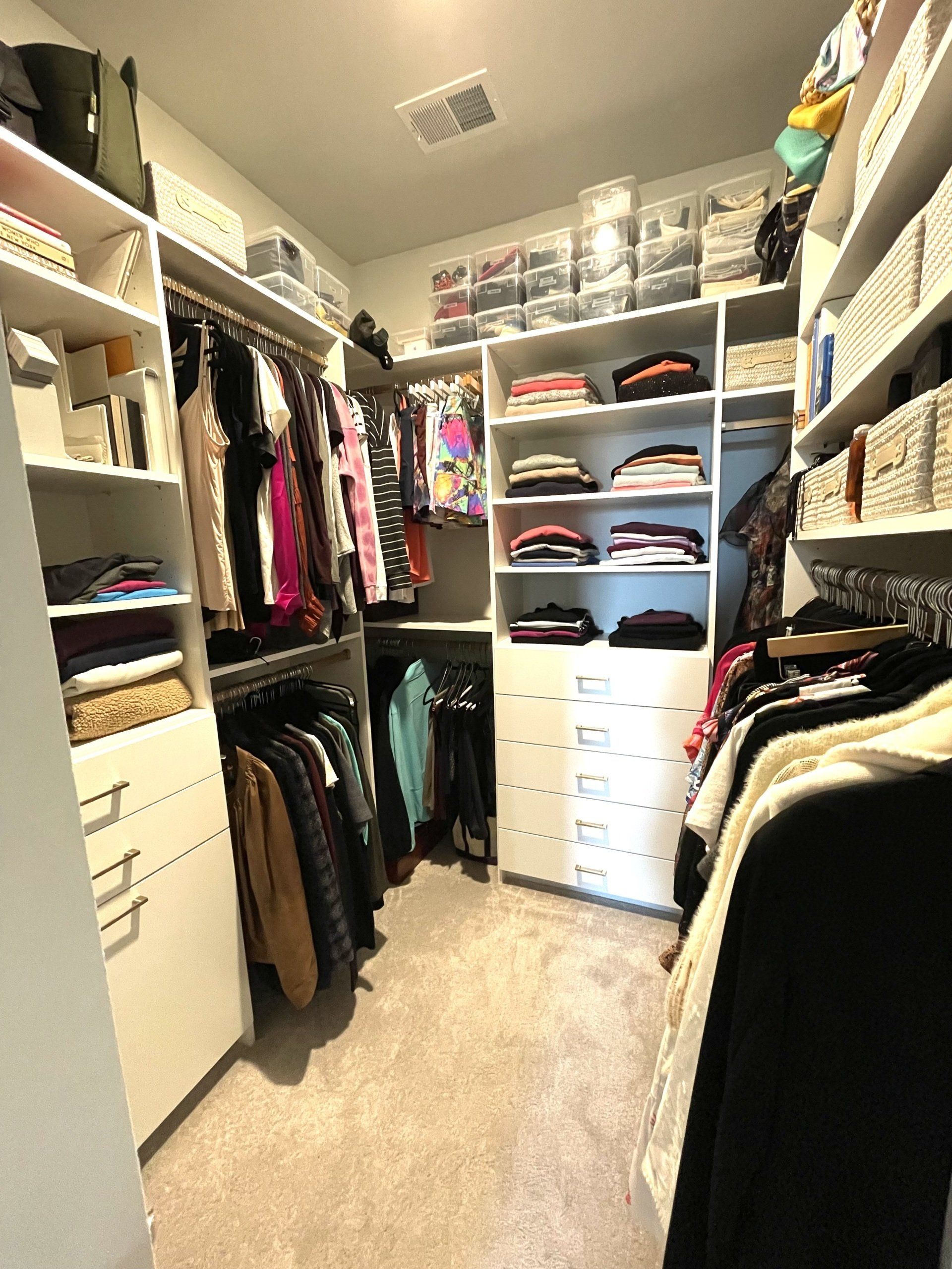 A walk in closet filled with lots of clothes and shelves.