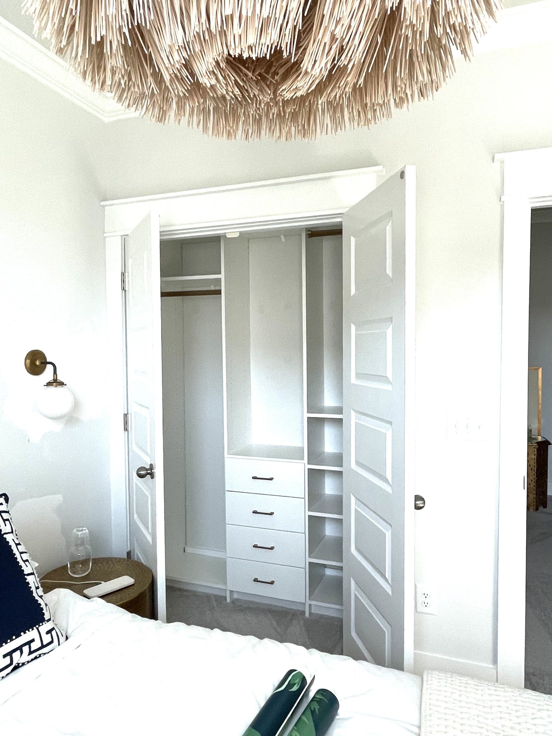 A bedroom with a bed and a closet with a chandelier hanging from the ceiling.
