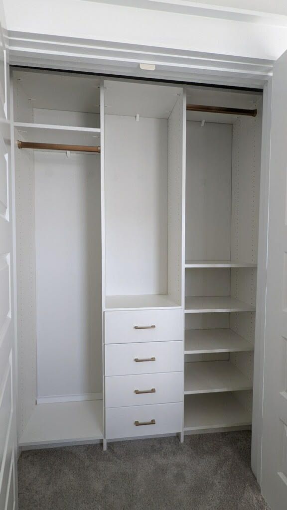 An empty closet with drawers and shelves in a bedroom.