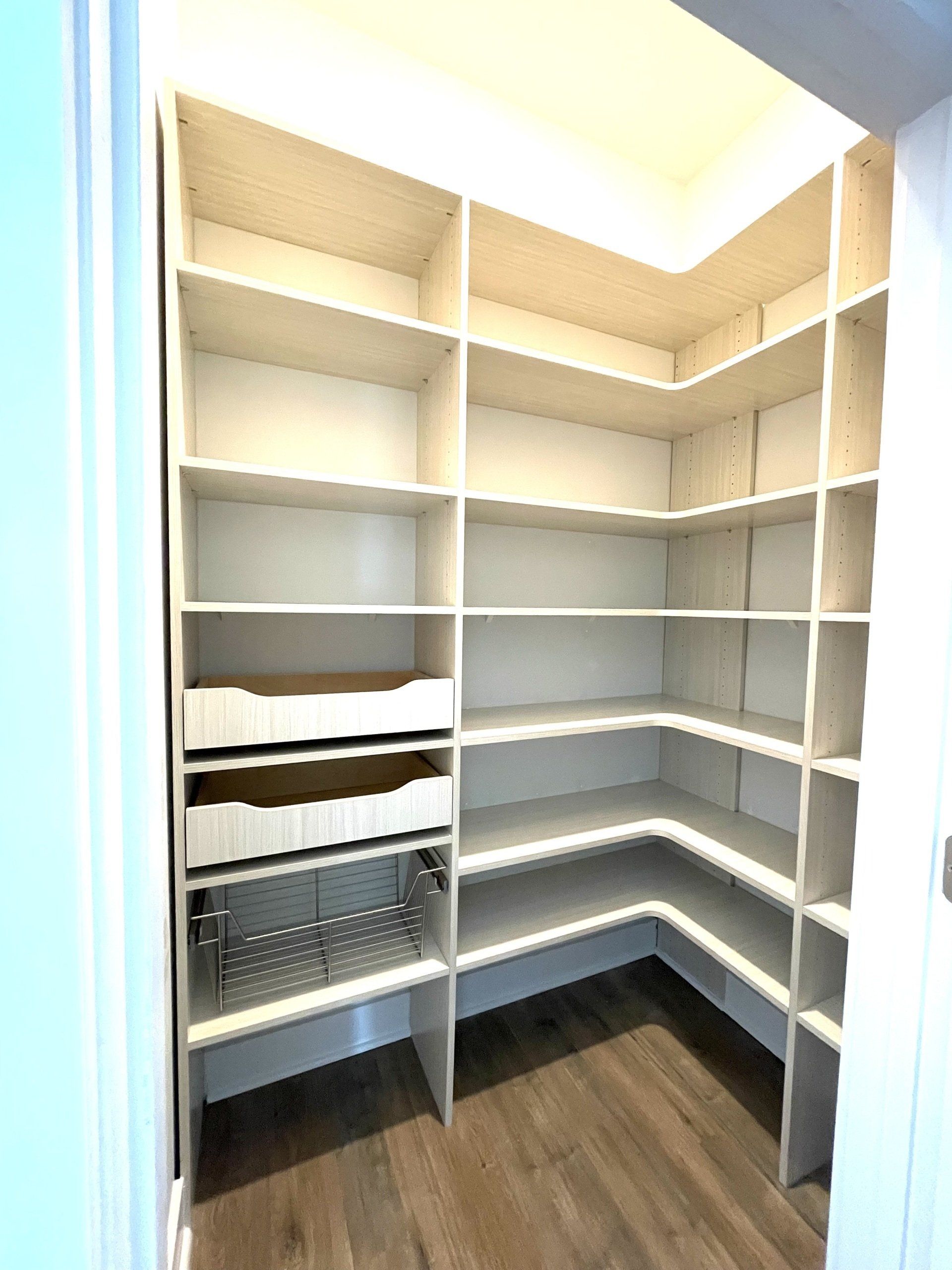 A walk in closet with lots of shelves and drawers.