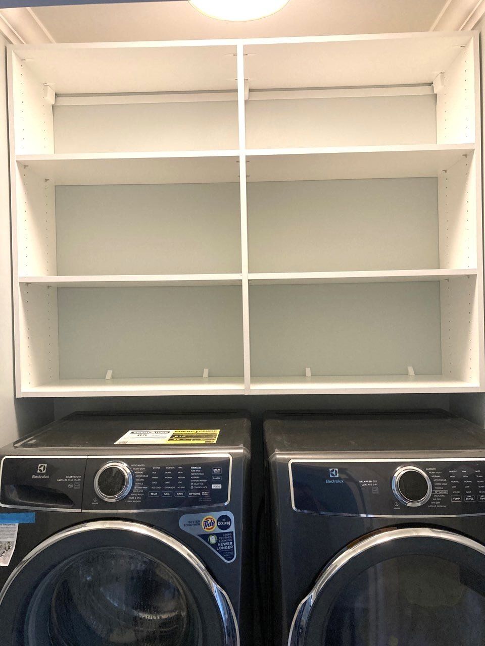 A washer and dryer in a laundry room with shelves above them