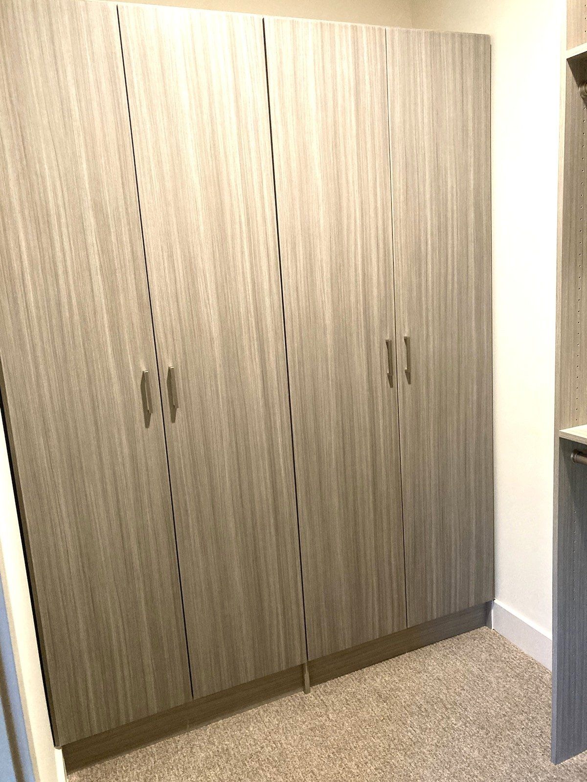 A closet with a lot of cabinets and a carpeted floor.