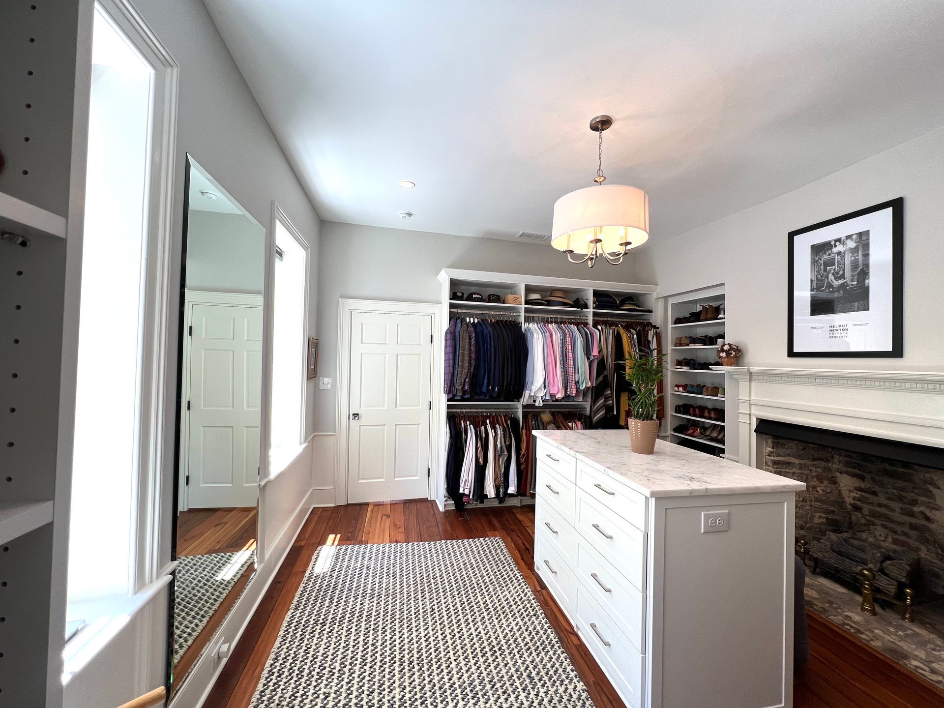 A walk in closet with lots of clothes and a fireplace.